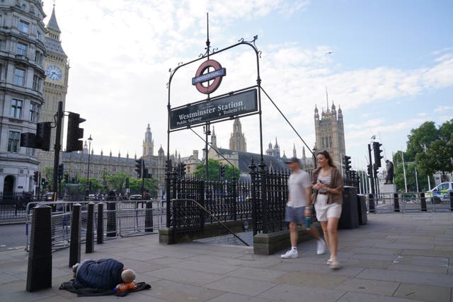 <p>A homeless person asleep on the street beside the entrance to Westminster underground station and in the shadows of Big Ben and the Houses of Parliament in central London.</p>