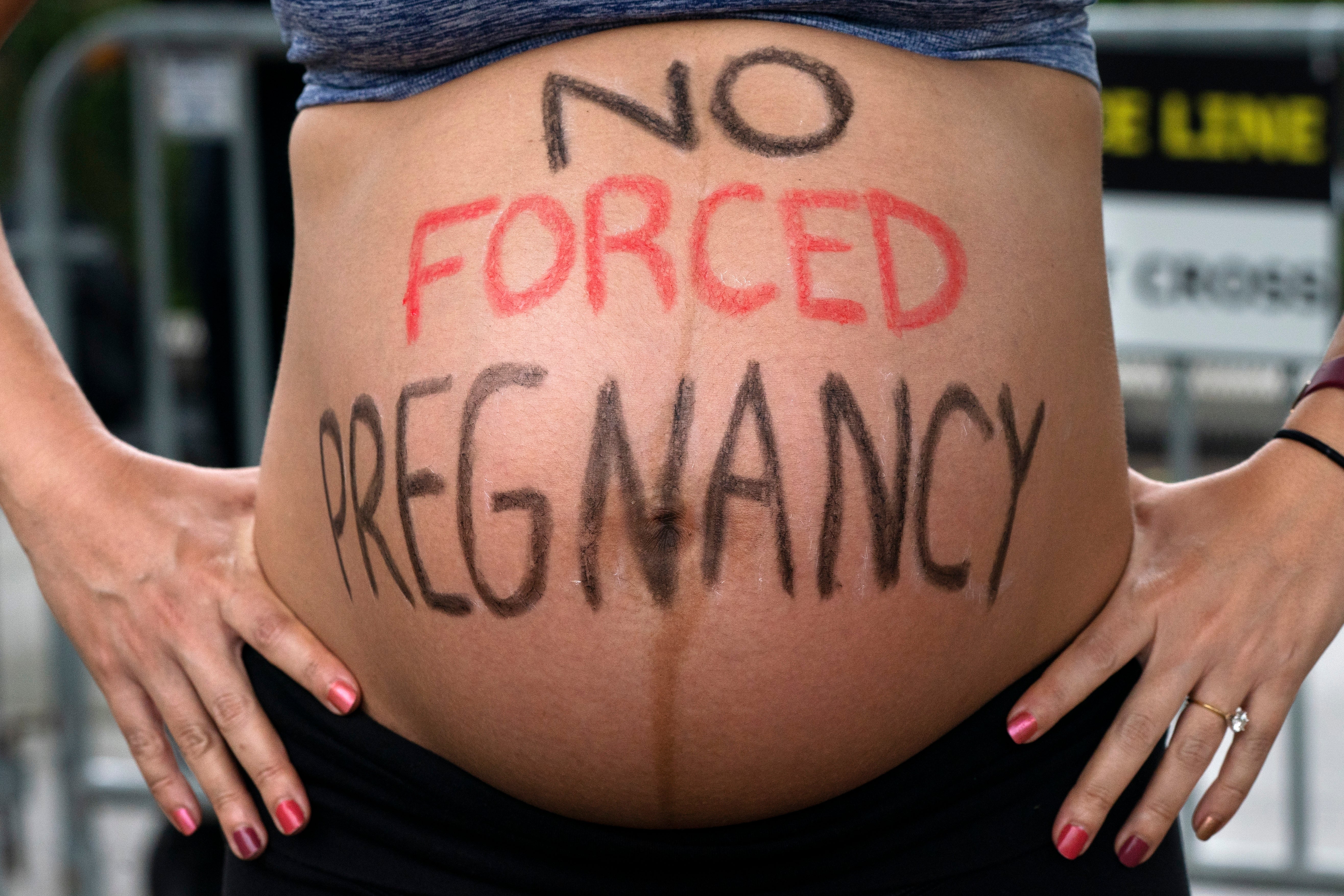 Krista Bywater shows her eight-months-pregnant belly during an abortion advocacy rally outside the Supreme Court