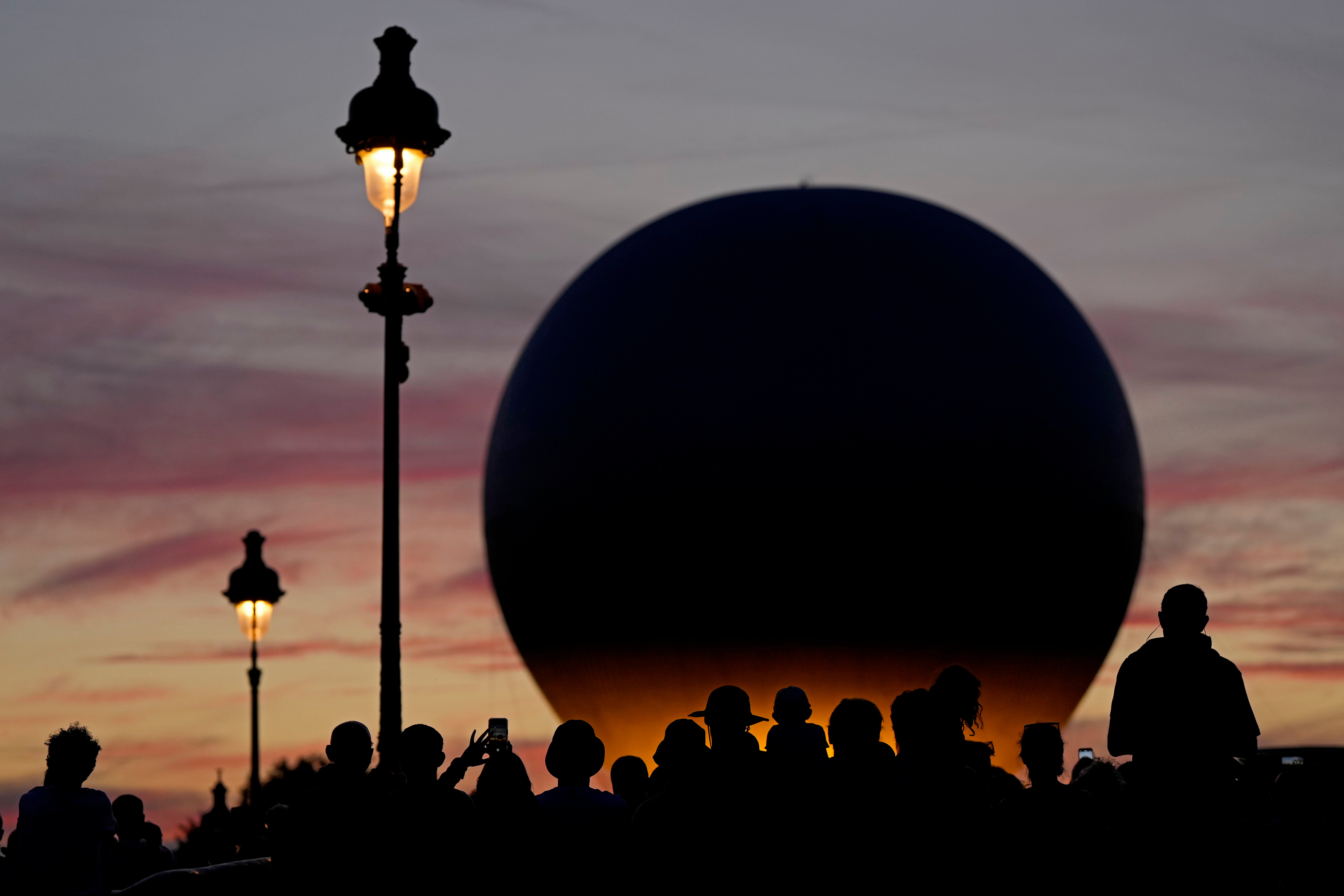 People wait for the balloon carrying the Olympic cauldron to rise above Tuileries Garden during the 2024 Summer Olympics