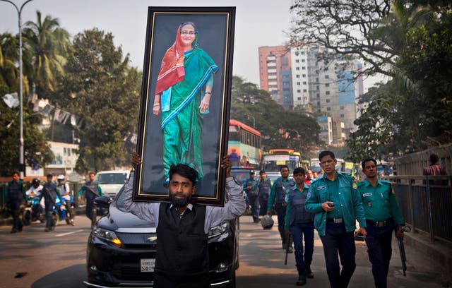 <p>Supporter of Awami League party carries a portrait of Sheikh Hasina during an election rally in Dhaka in 2018</p>