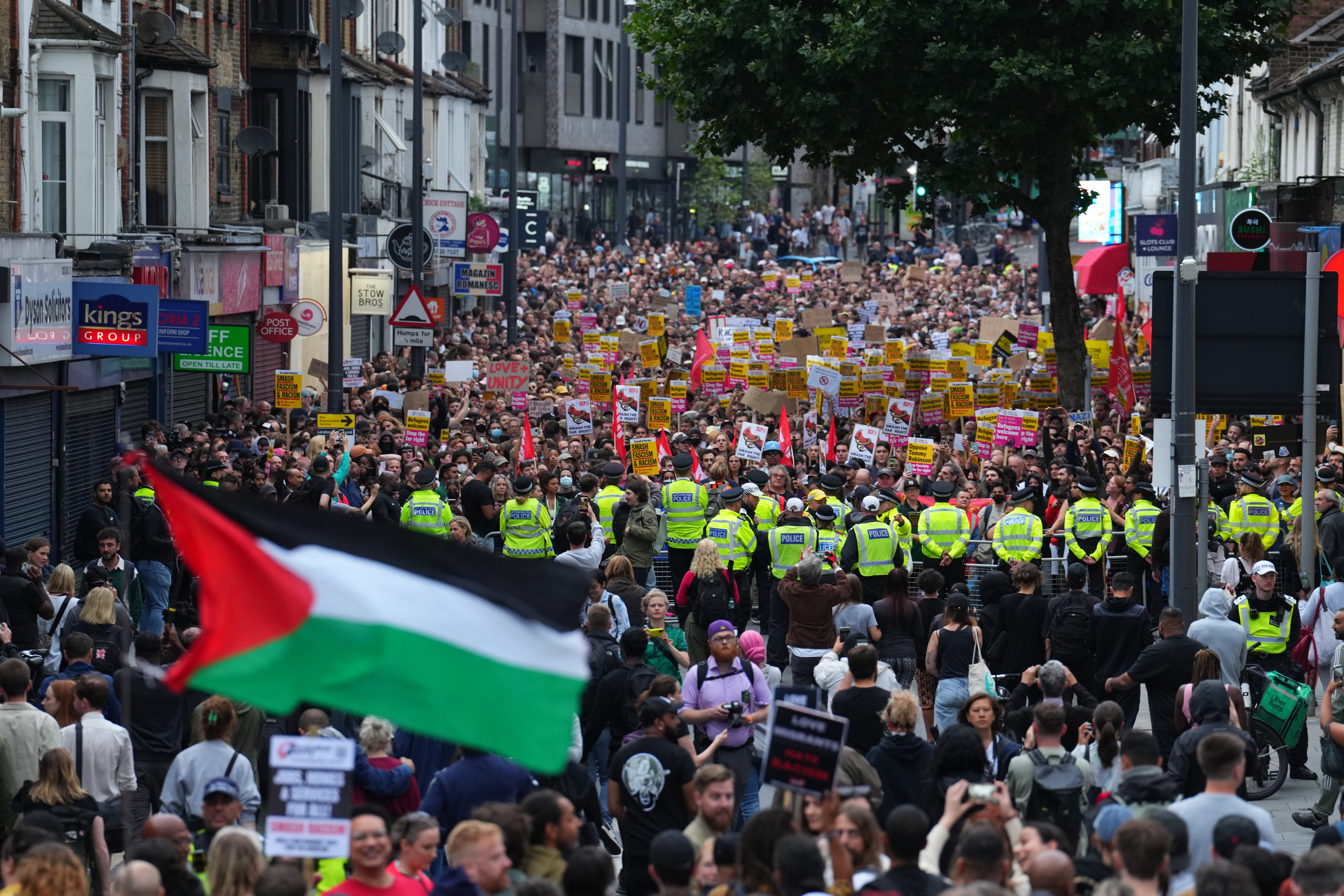A Palestinian flag is waved as anti-racism counter protesters assemble ahead of a potential anti-immigration protest in Walthamstow