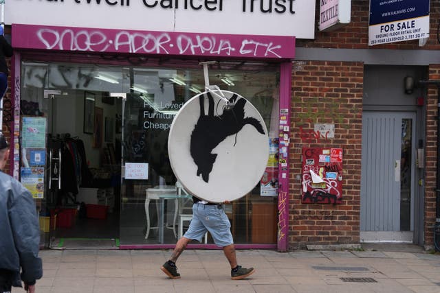 The new howling wolf artwork by Banksy being carried away (Jordan Pettitt/PA)