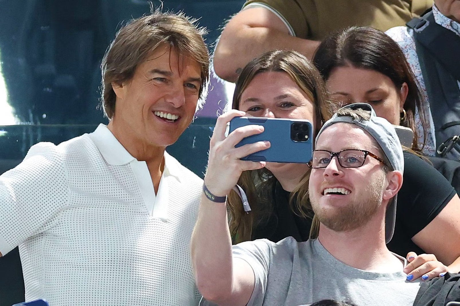 Man of the people: Tom Cruise poses for selfies with fans during one of his (many) public appearances this summer, this time at the Paris Olympics