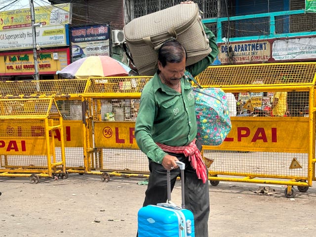 <p>A porter carries the luggage of a Bangladeshi national upon his arrival in India</p>