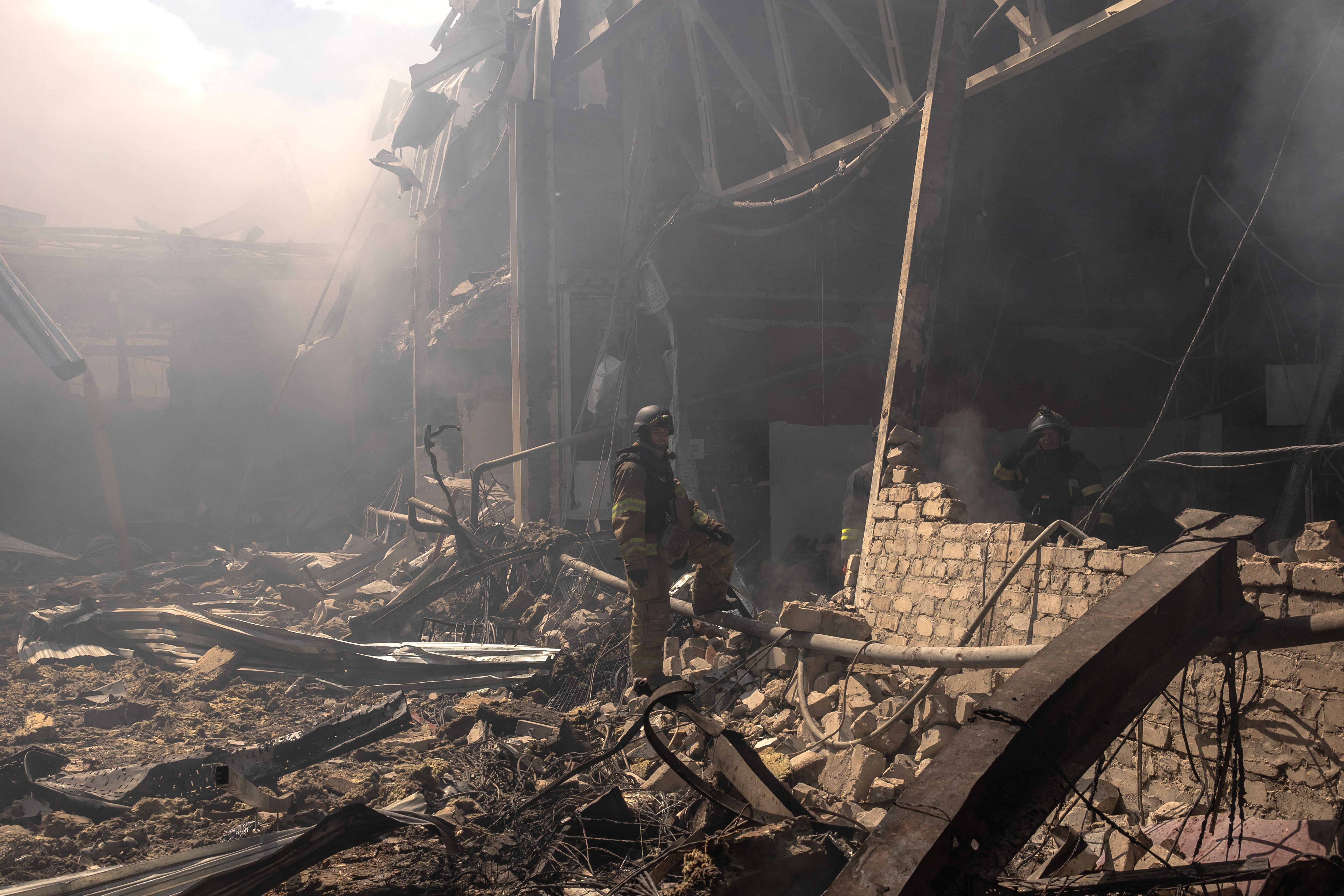 Ukrainian emergency and rescue personnel stand among the rubble as they work at the site of the supermarket destroyed after a Russian attack in Kostiantynivka, eastern Donetsk region.