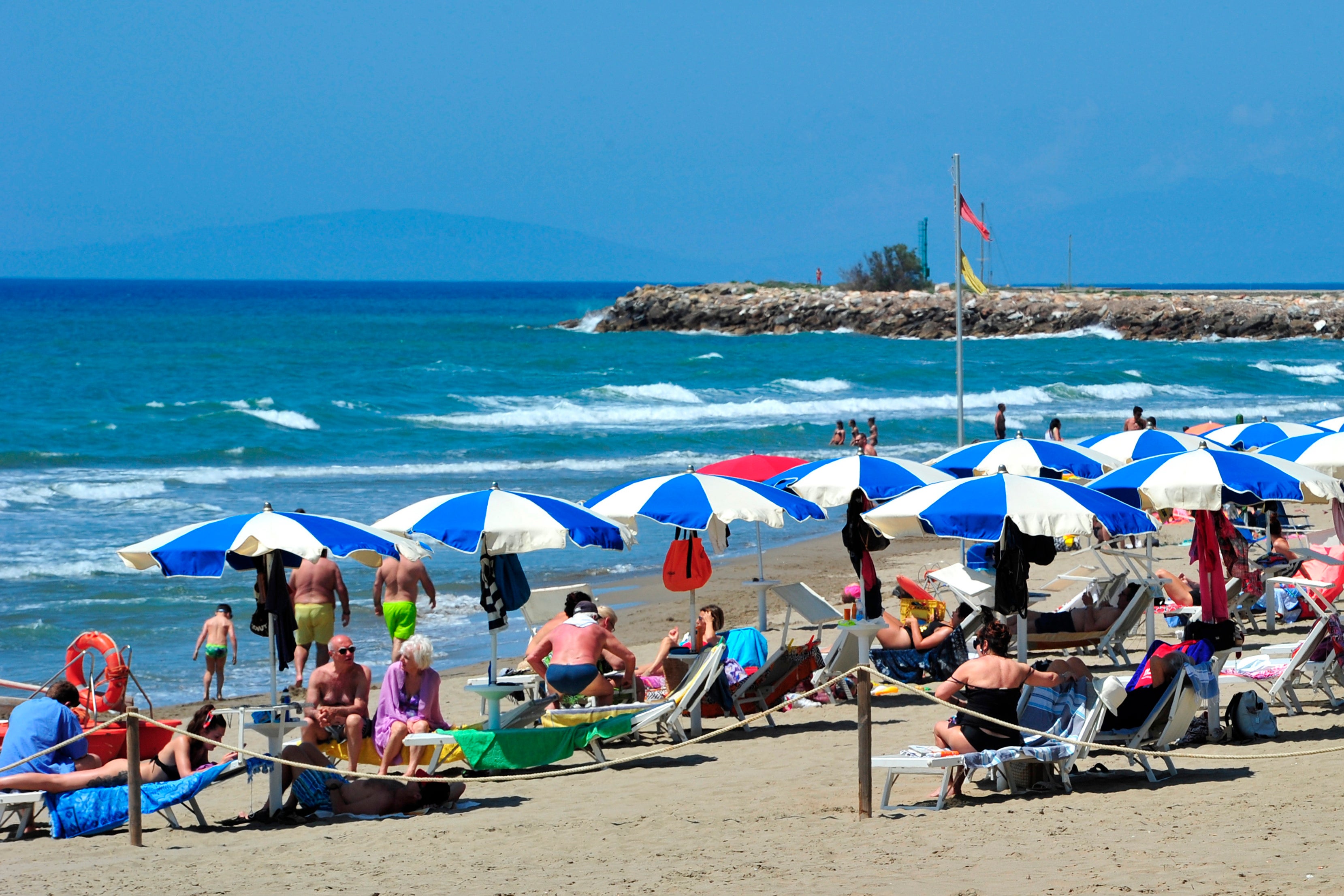 People enjoy a sunny day at an establishment on the beach in Tuscany’s Castiglione della Pescaia, Italy