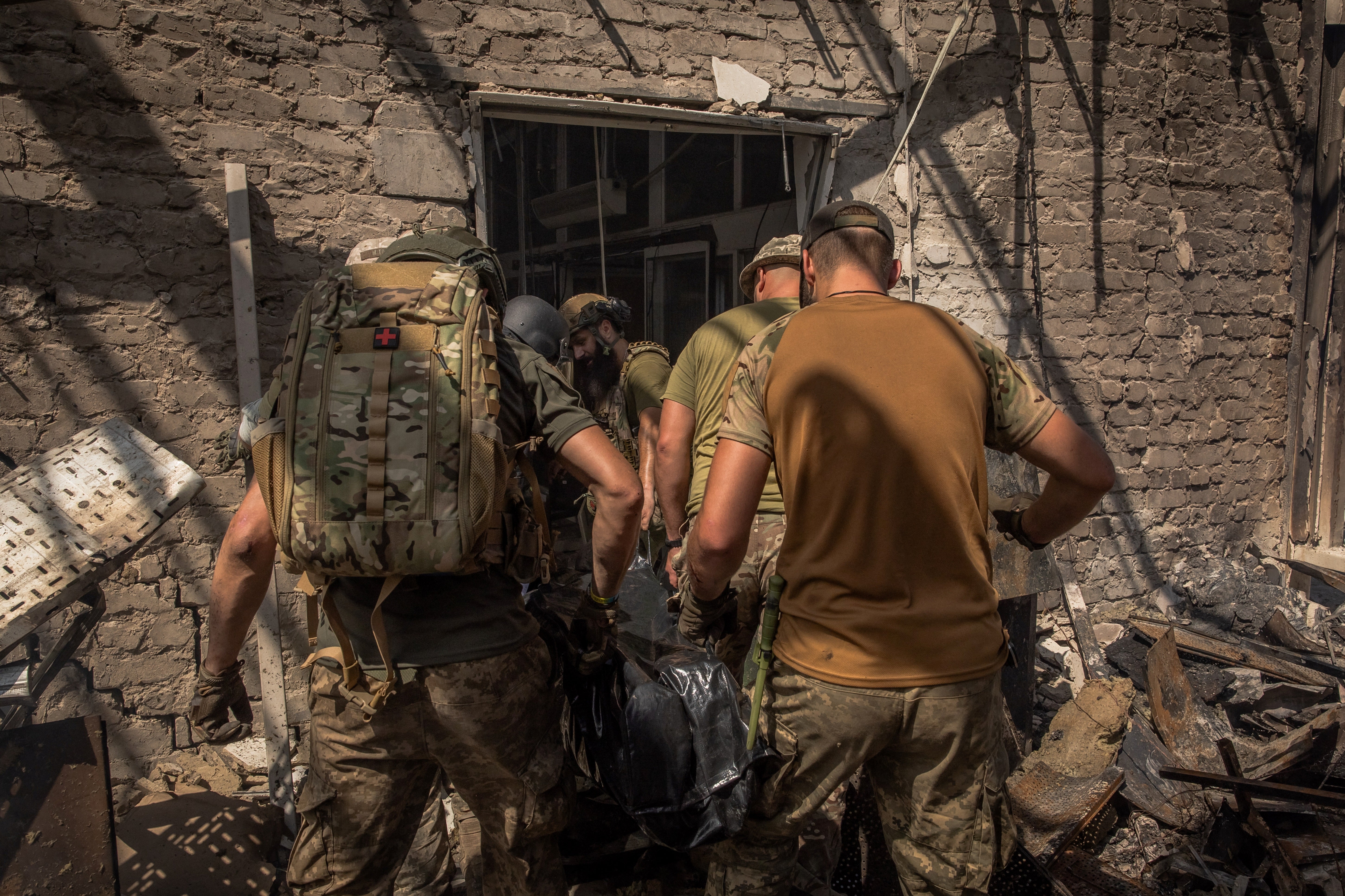 Ukrainian emergency and rescue personnel together with military members carry a body of a victim killed following a Russian strike on a supermarket, in Kostyantynivka, eastern Donetsk region