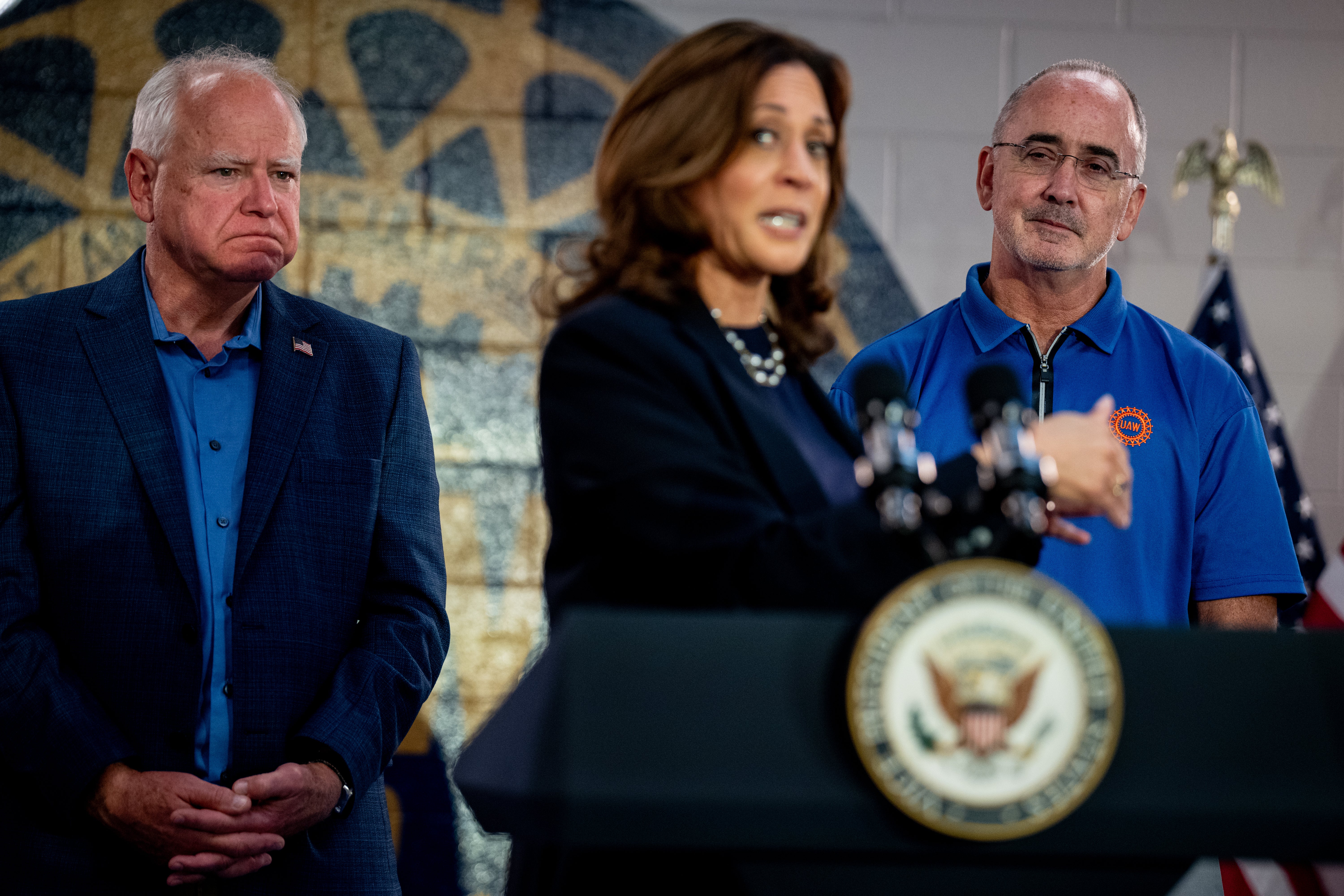 Kamala Harris speaks alongside United Automobile Workers (USA) President Shawn Fain (right) and her running mate Tim Walz (left) at a United Auto Workers Local 900 branch in Michigan on August 8.