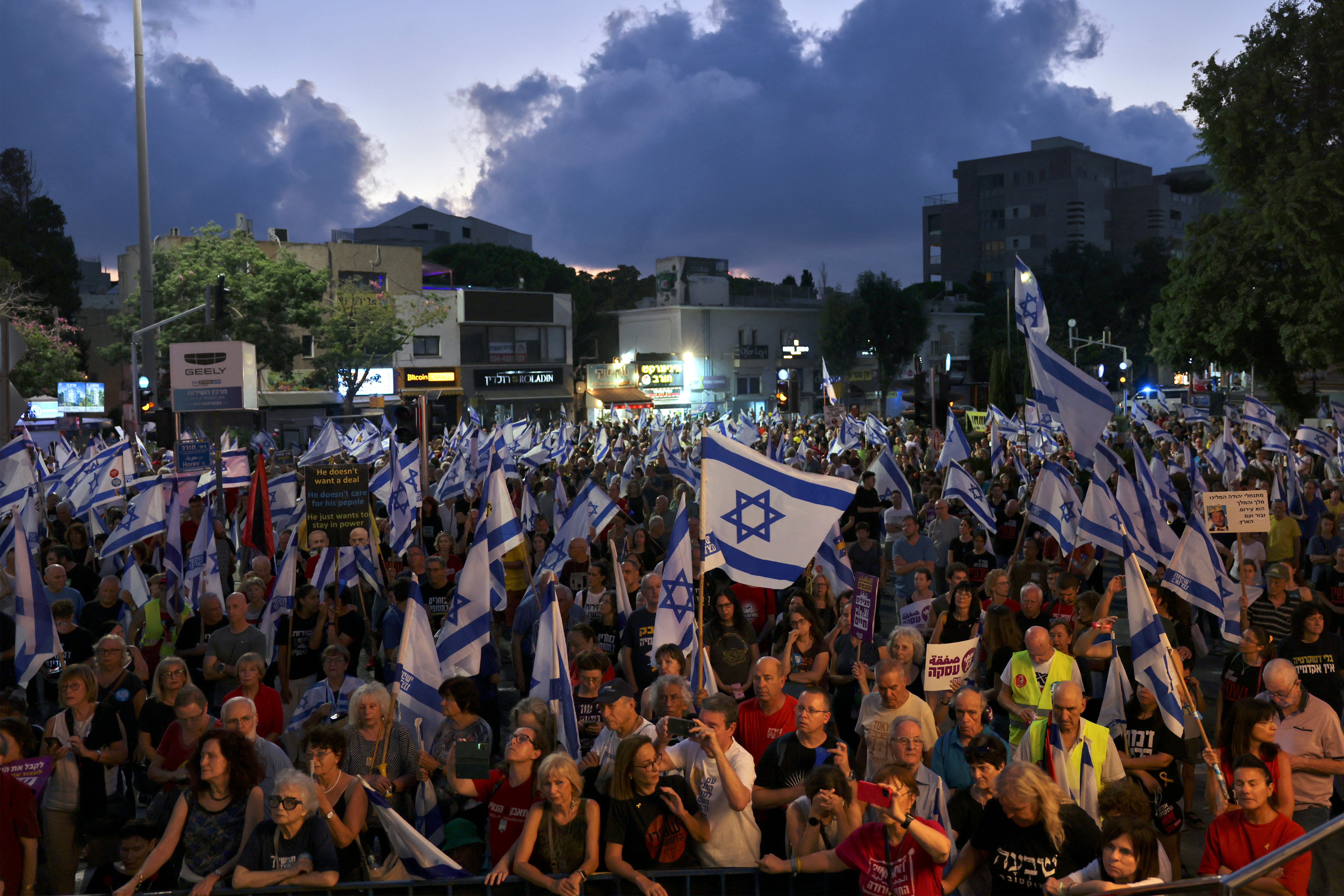 Relatives and supporters of Israelis held hostage by Palestinian militants in Gaza since the October 7 attacks lift flags and placards as they demonstrate calling for their release in the port city of Haifa