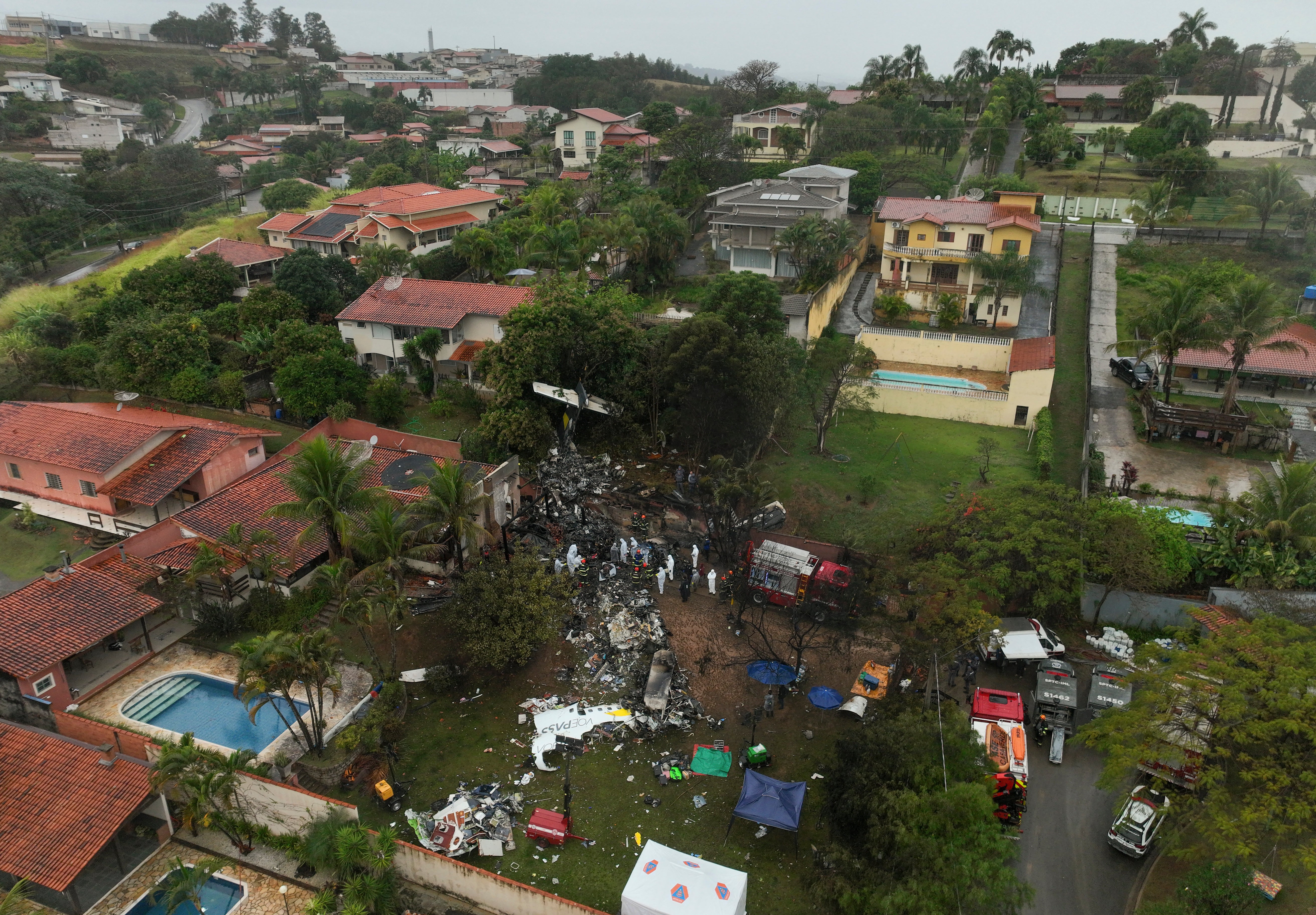 Firefighters and rescue crews work in a residential area where a plane carrying 62 people crashed in Vinhedo.