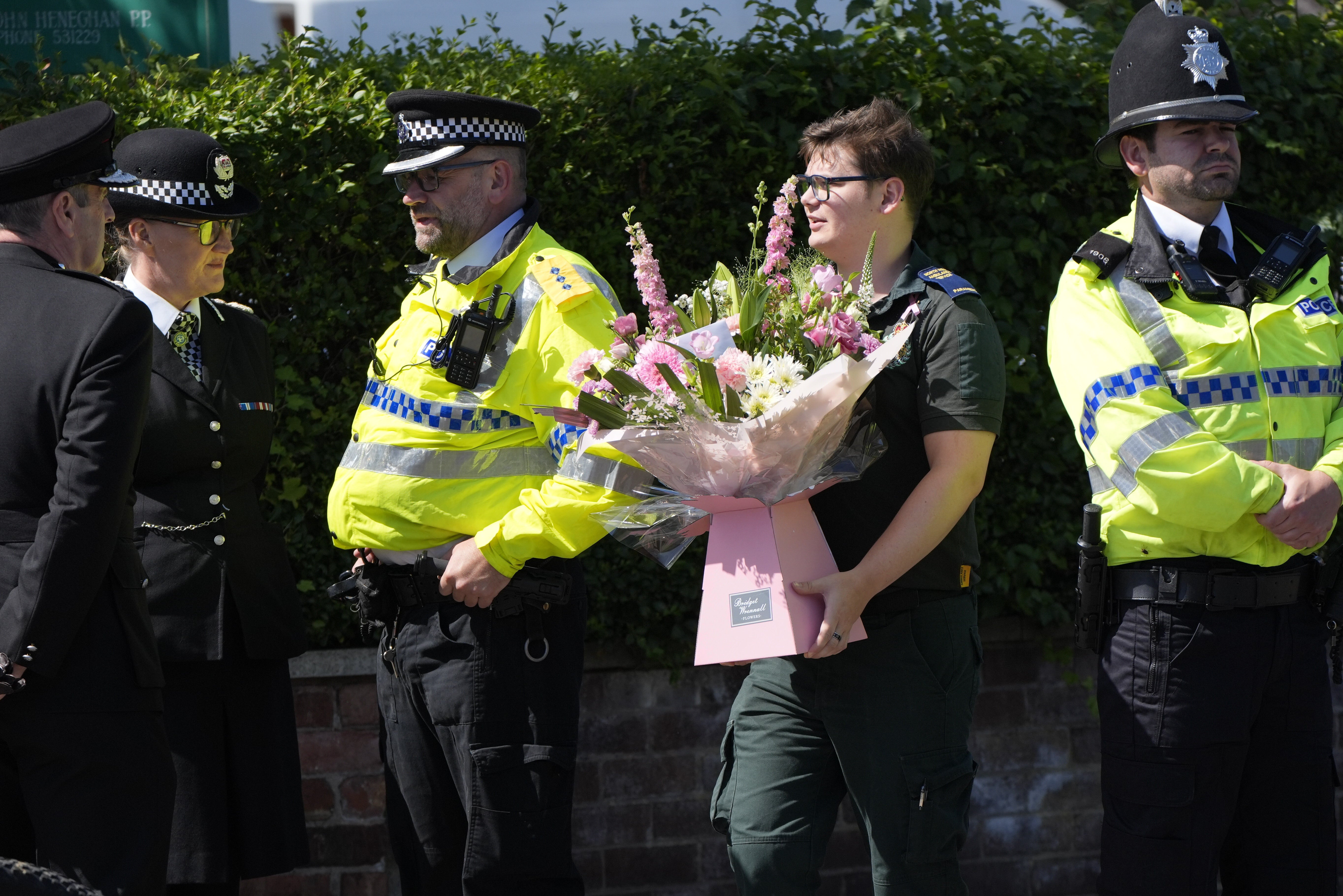 A paramedic carries flowers ahead of the funeral