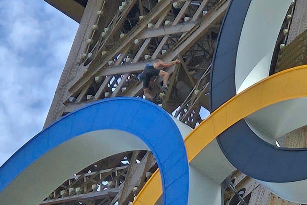 A man climbs the Eiffel Tower, during the 2024 Summer Olympics