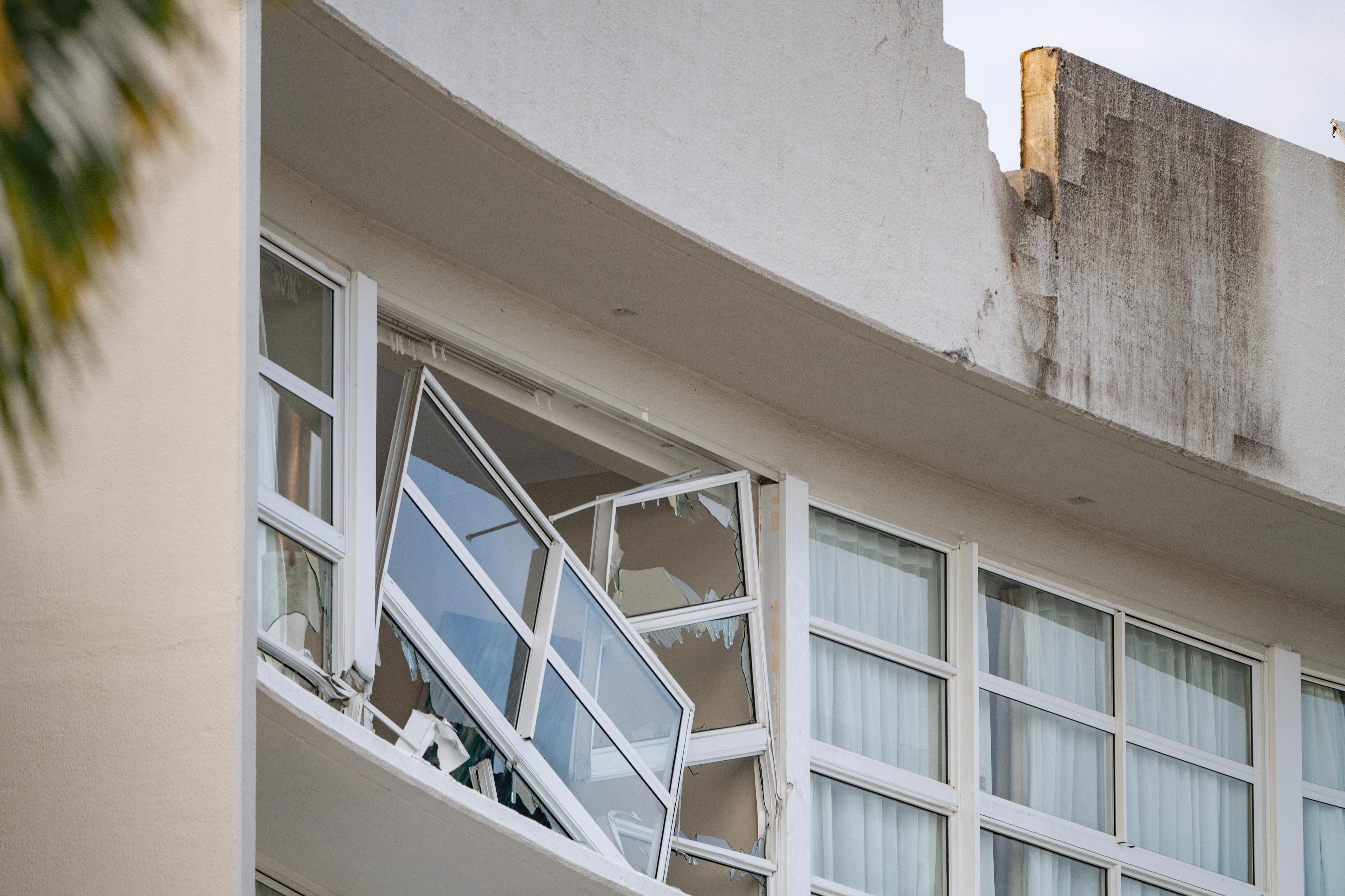 A broken window and damaged roof are seen at the Double Tree by Hilton hotel in Cairns, Australia, after a helicopter crashed into the roof of the hotel on August 12, 2024