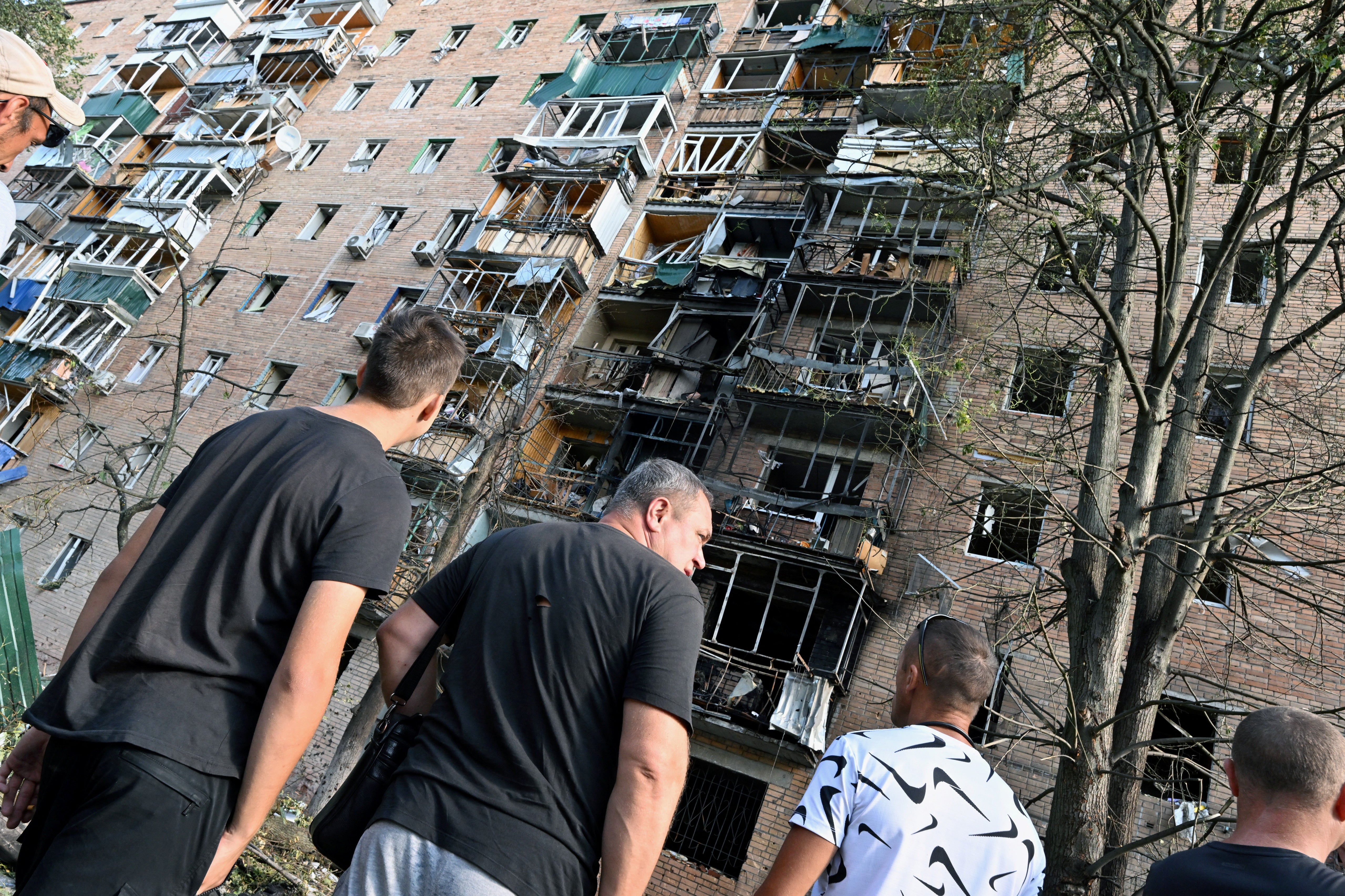 People gather in the courtyard of a multi-storey residential building, which according to local authorities was hit by debris from a destroyed Ukrainian missile