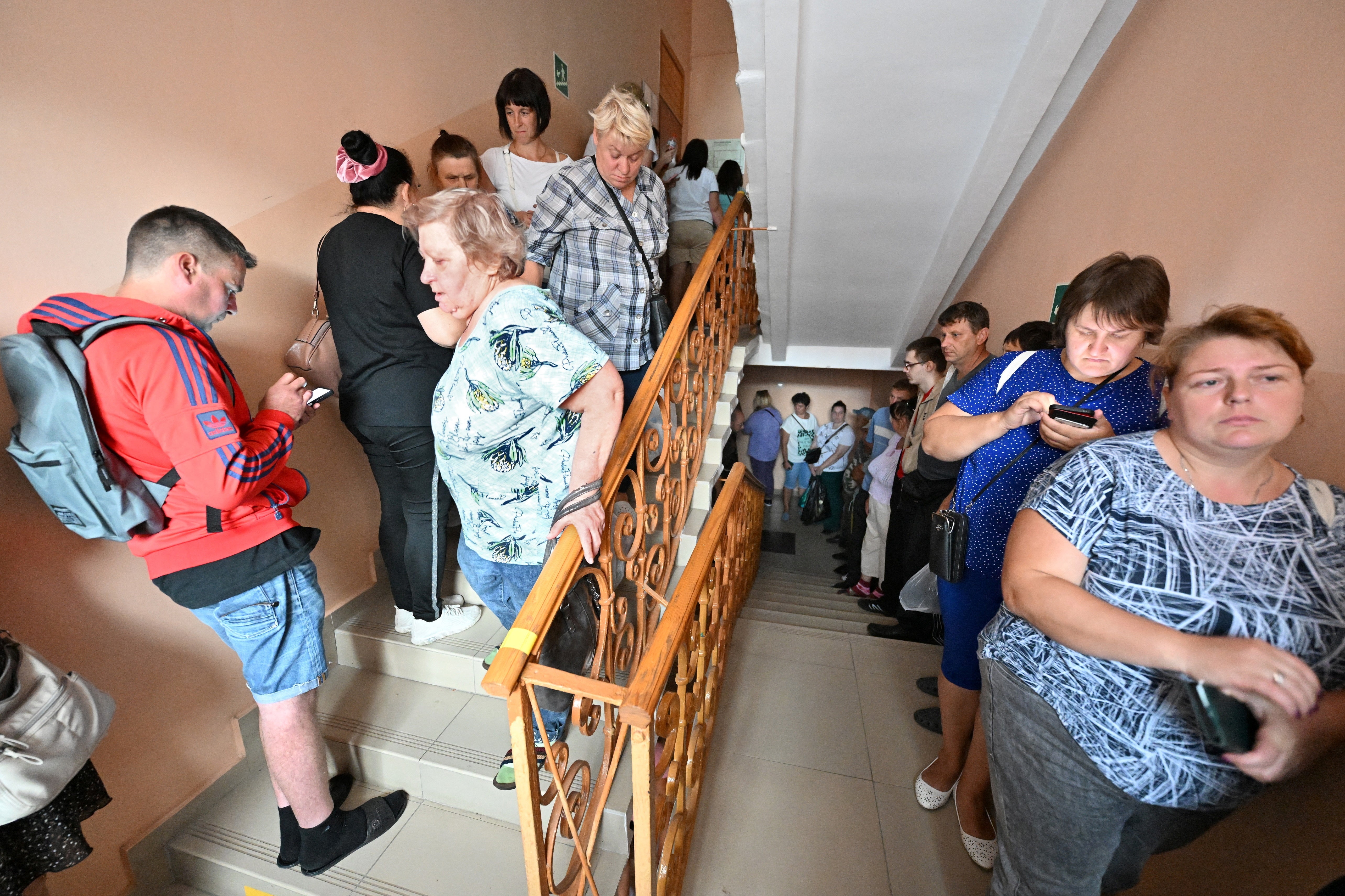 People queue to receive humanitarian aid intended for residents of the Kursk region, who were evacuated following an incursion of Ukrainian troops