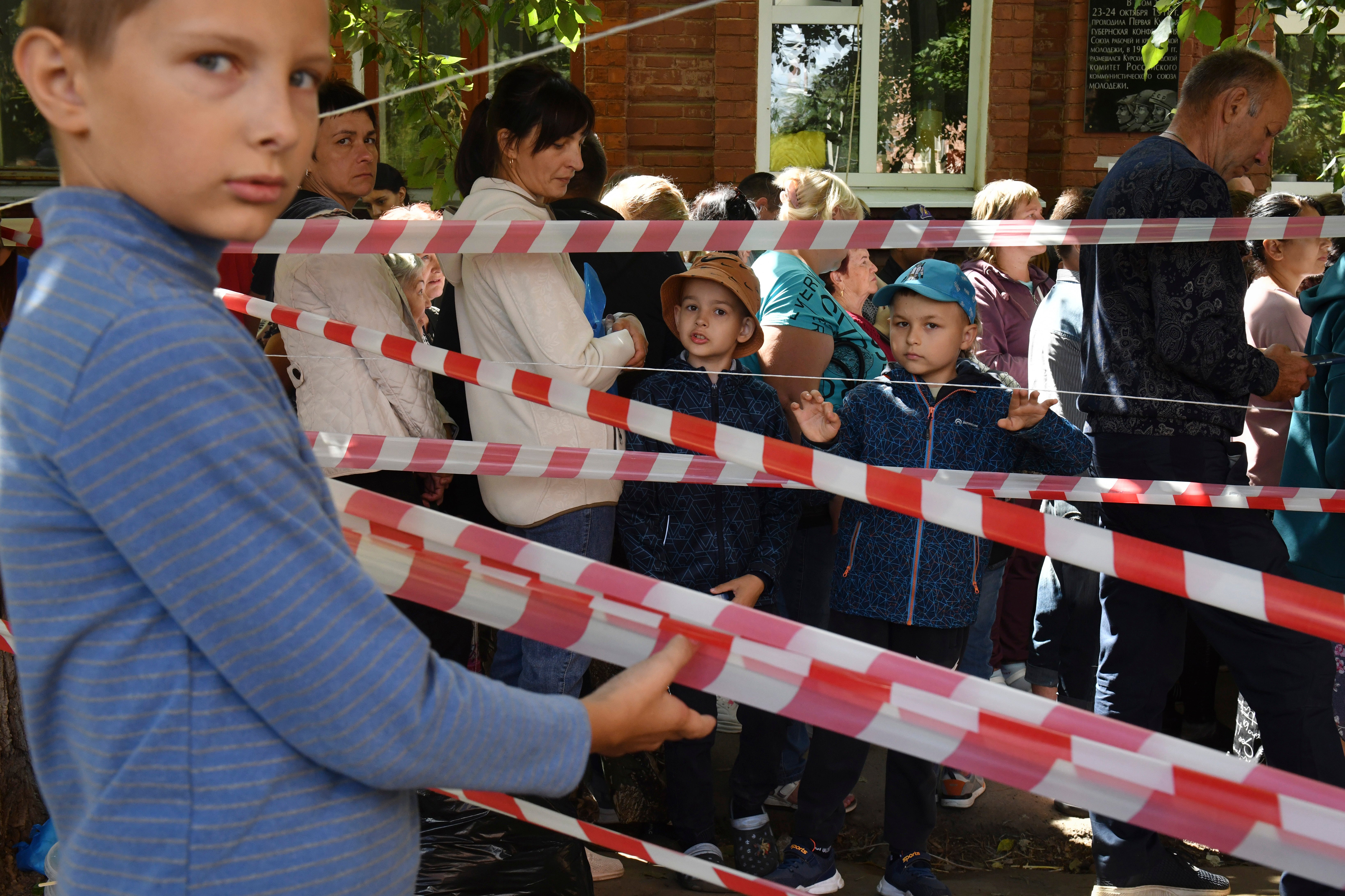 Young children are seen waiting behind makeshift barriers in Kursk