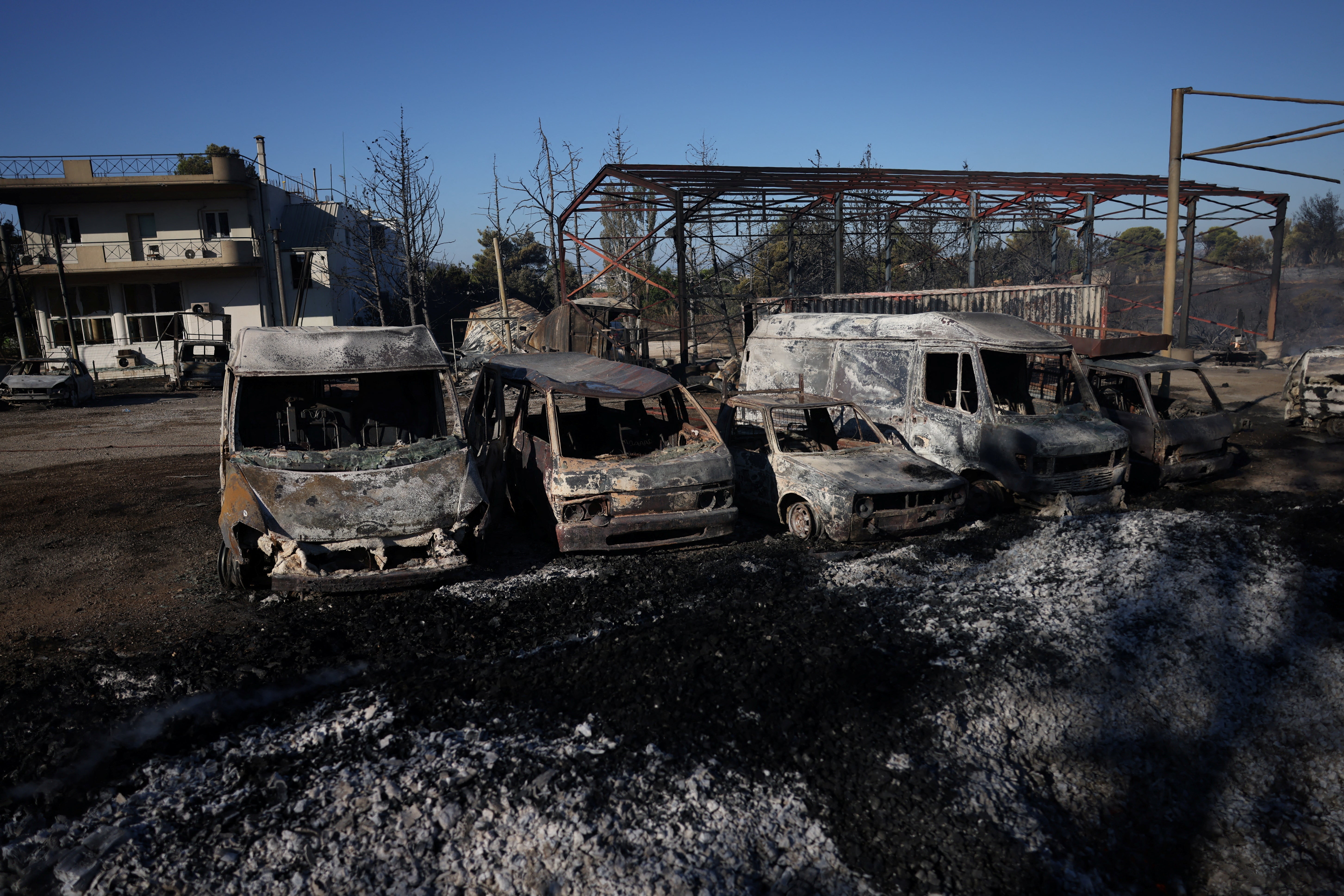 Burned cars are pictured outside a damaged factory following a wildfire in the Penteli area near Athens, Greece