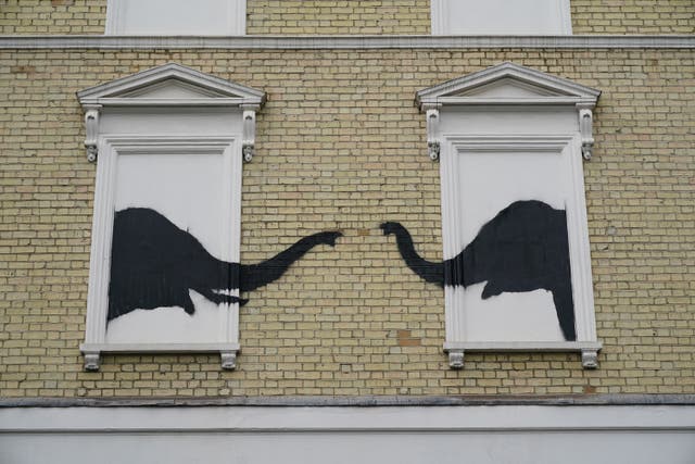 <p>A Banksy artwork depicting two elephants poking their heads out of blocked out windows was unveiled on the side of a building in Chelsea on Tuesday (Yui Mok/PA)</p>