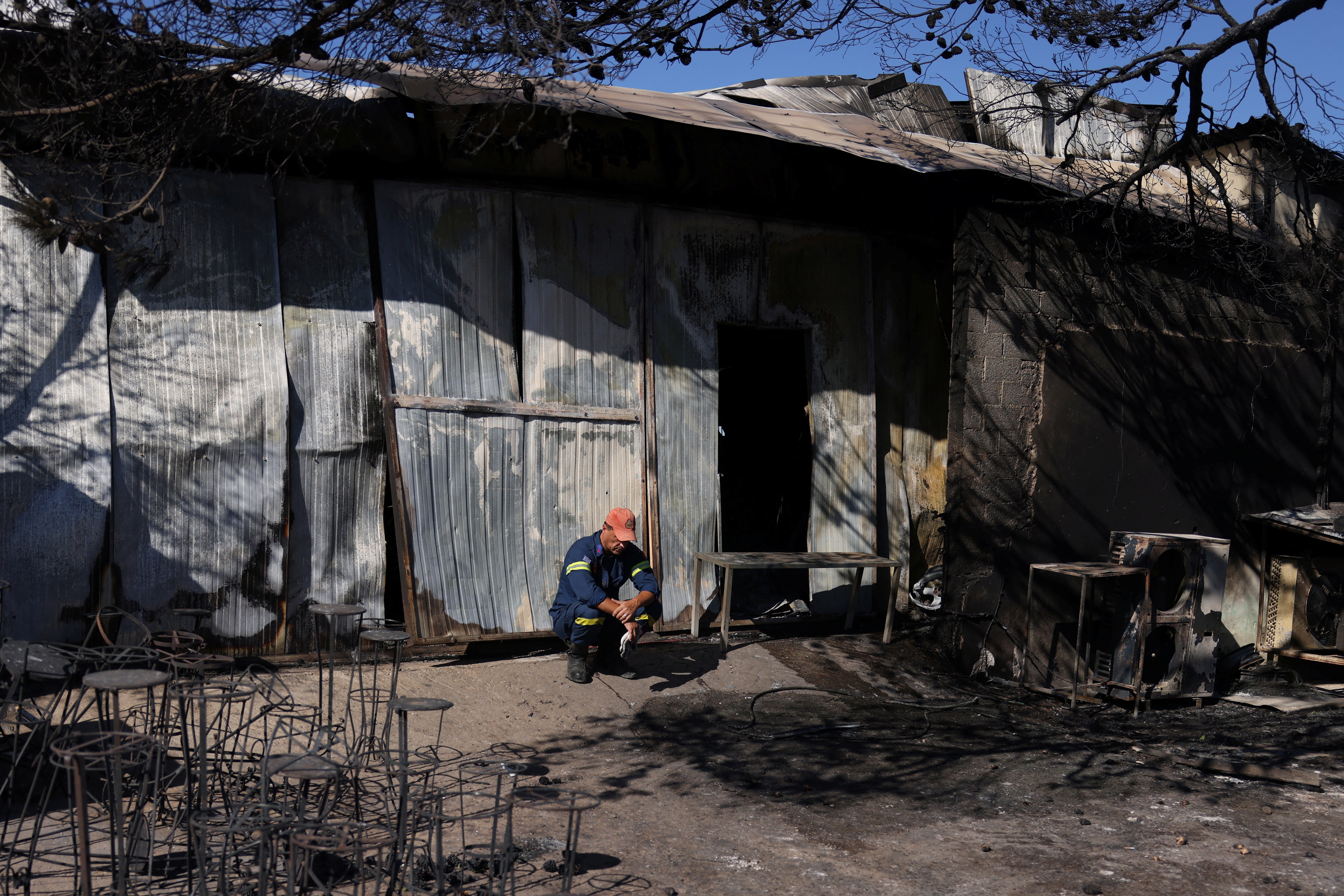 A fireman rests outside a factory where one woman was found dead, following the wildfire in Halandri suburb in Athens, Greece