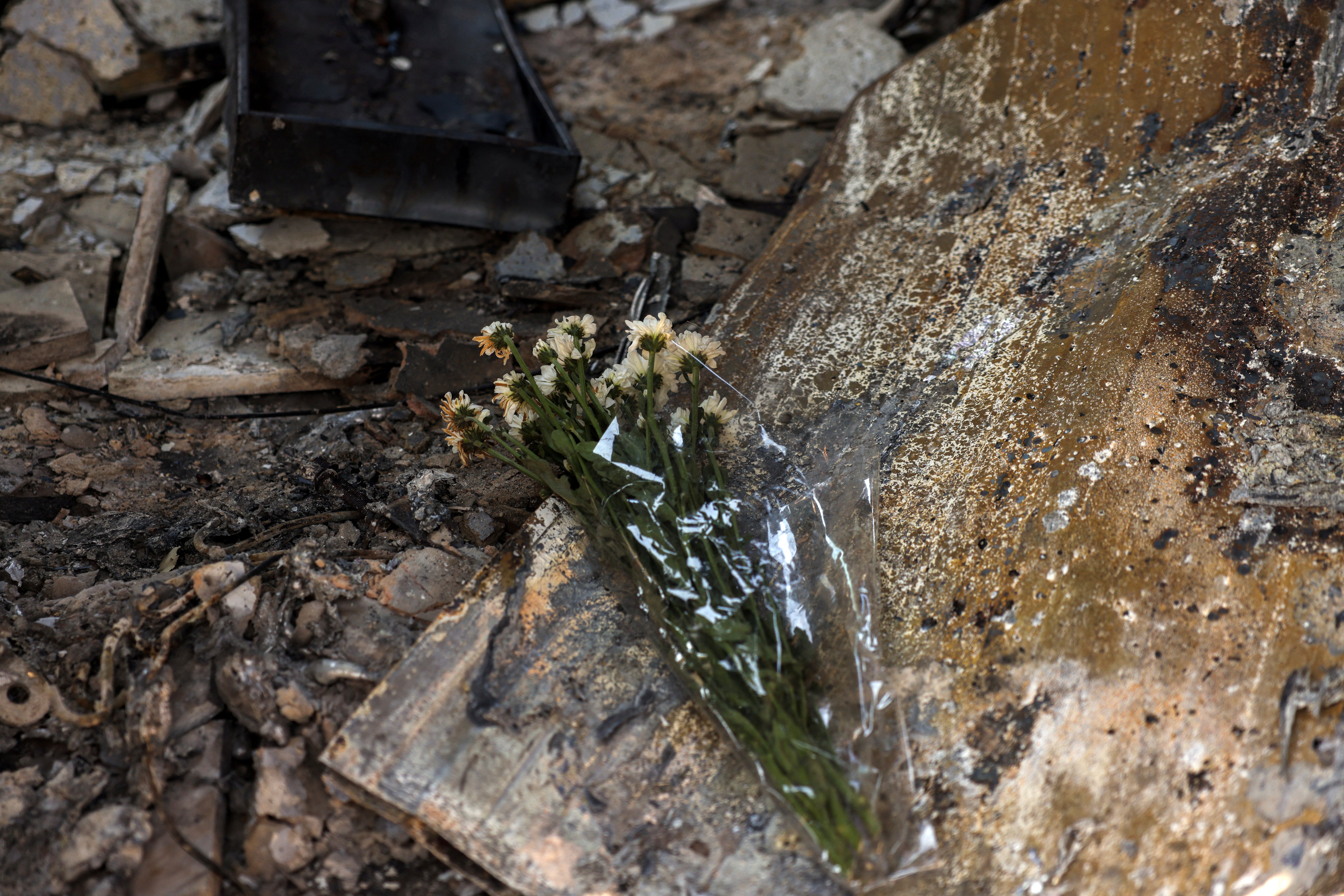 Blumen wurden in einem ausgebrannten Gebäude niedergelegt, in dem eine Frau nach einem Waldbrand in Vrilissia in der Nähe von Athen, Griechenland, tot aufgefunden wurde.