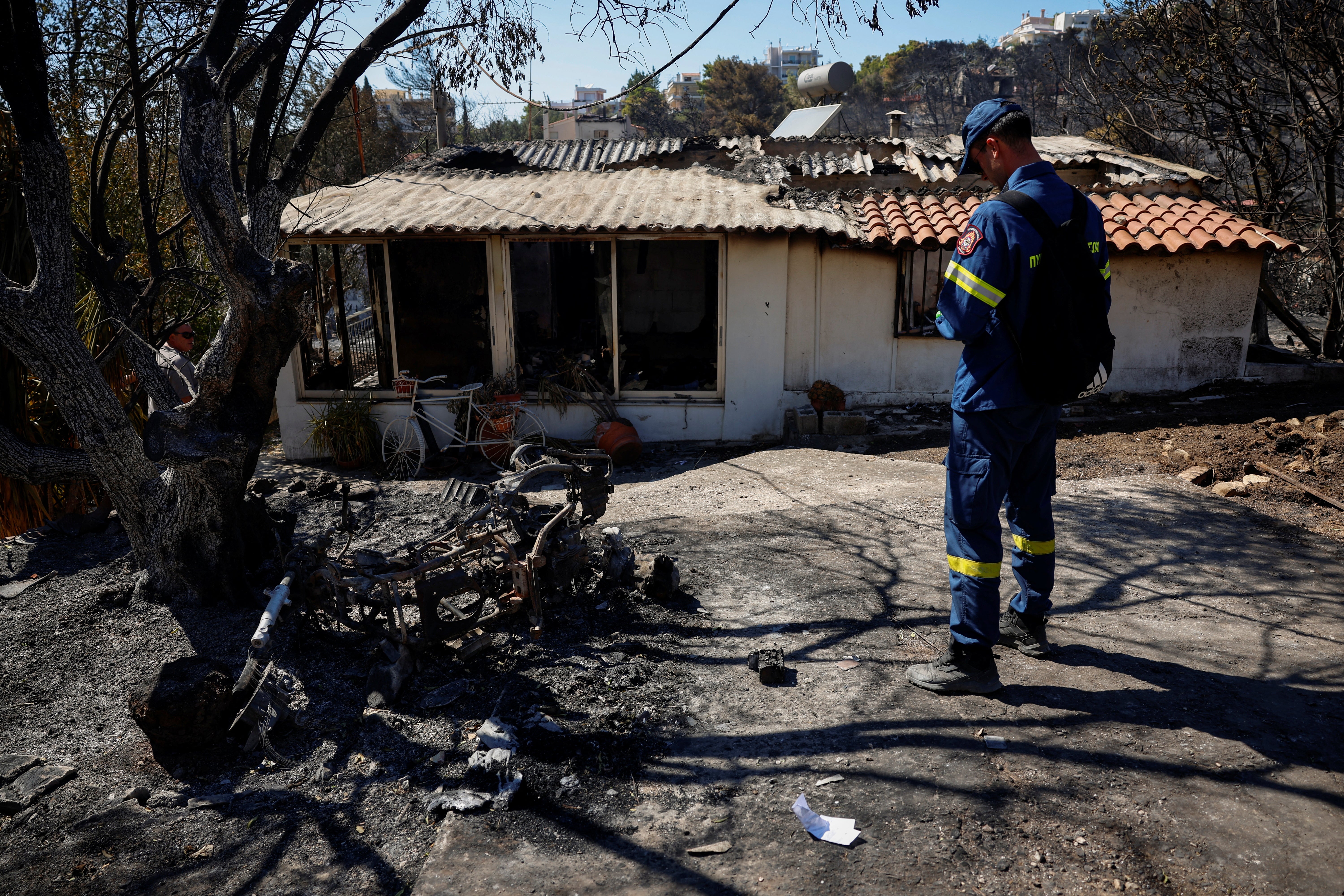 A firefighter visits burned properties for the first registering of damages, following the wildfire in Halandri suburb in Athens