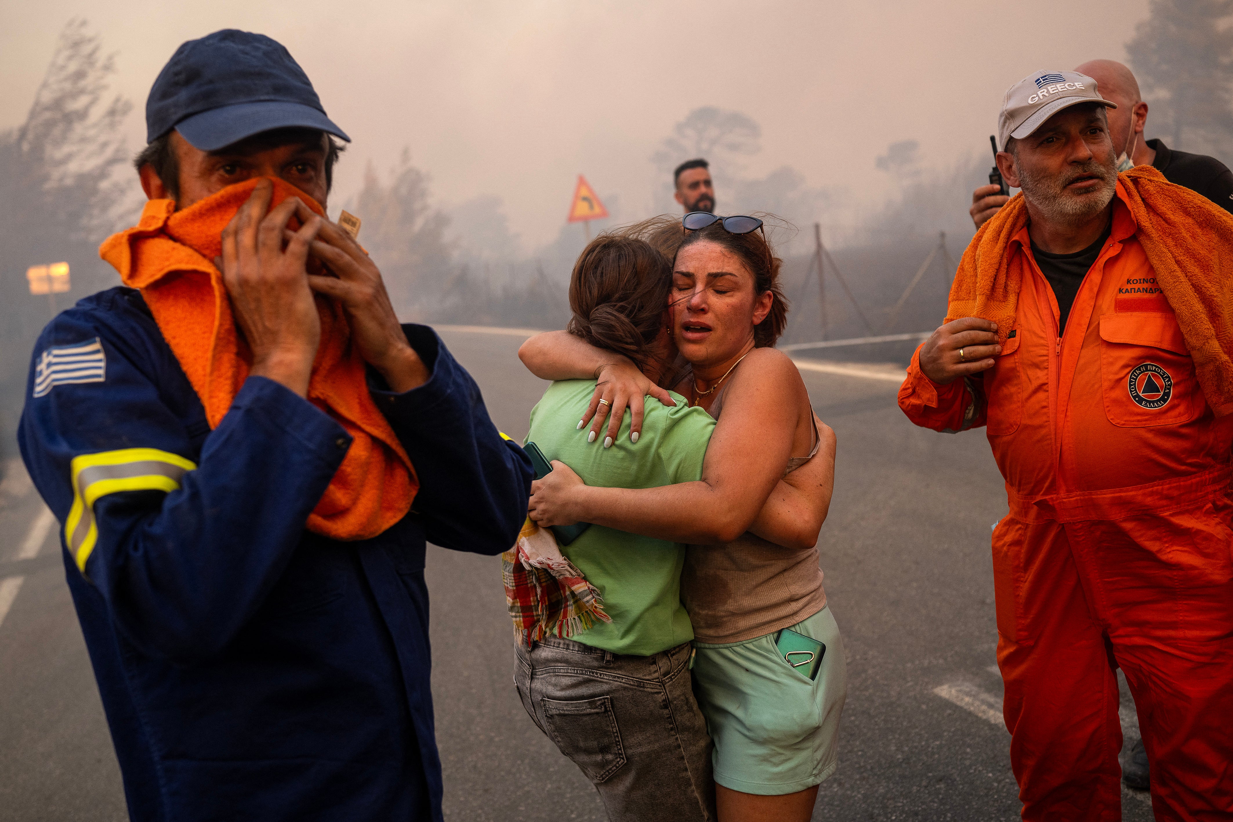 Zwei Frauen umarmen sich, nachdem sie bei einem Waldbrand in Varnavas nördlich von Athen gerettet wurden