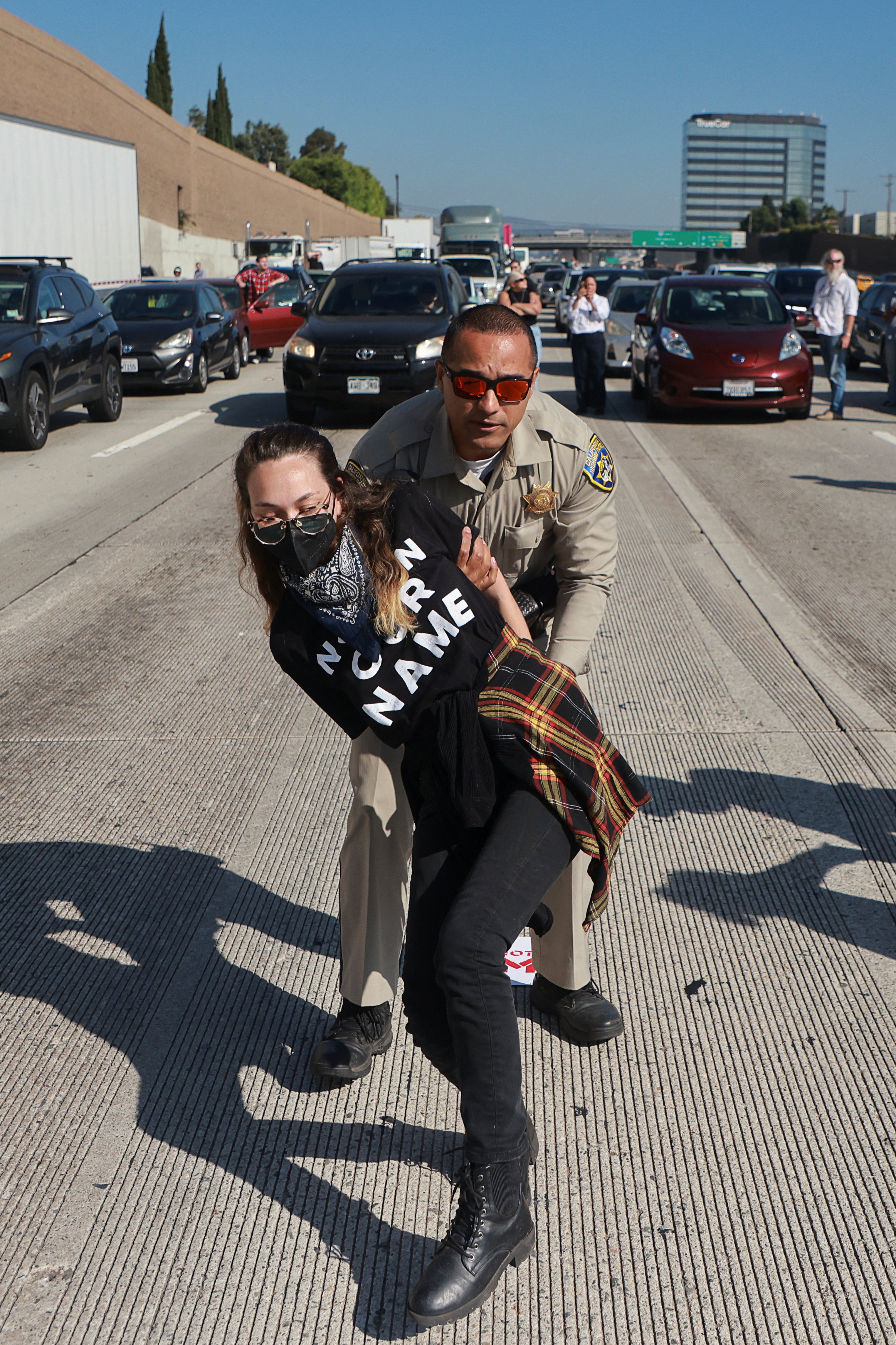 A highway patrol officer detains a supporter of a ceasefire and arms embargo, amid the Israel-Hamas war in Gaza, during a protest blocking the 405 freeway's southbound lanes, in Los Angeles, California, U.S. August 13, 2024.