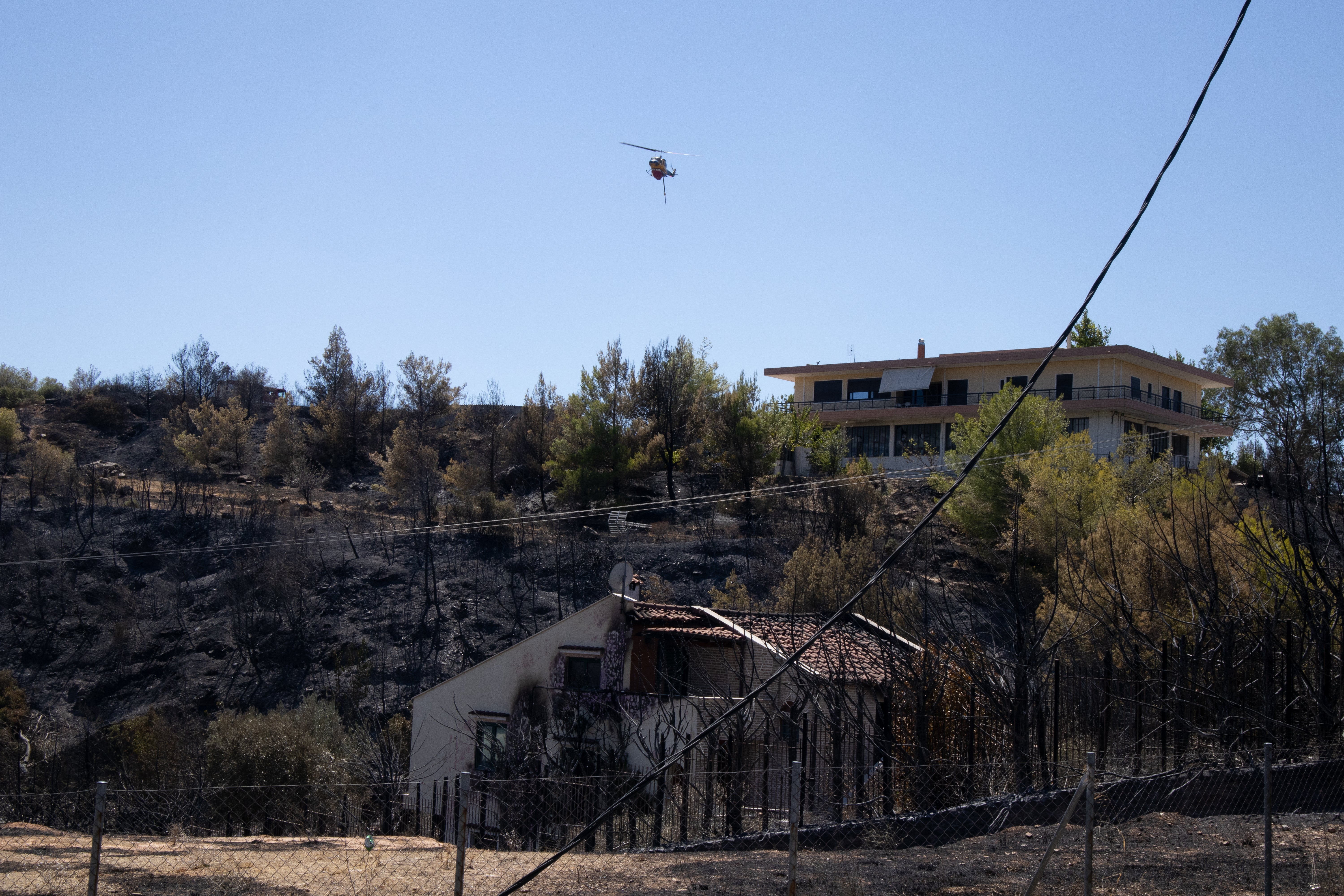 A firefighter helicopter hovers above a building damaged by fire near Marathon