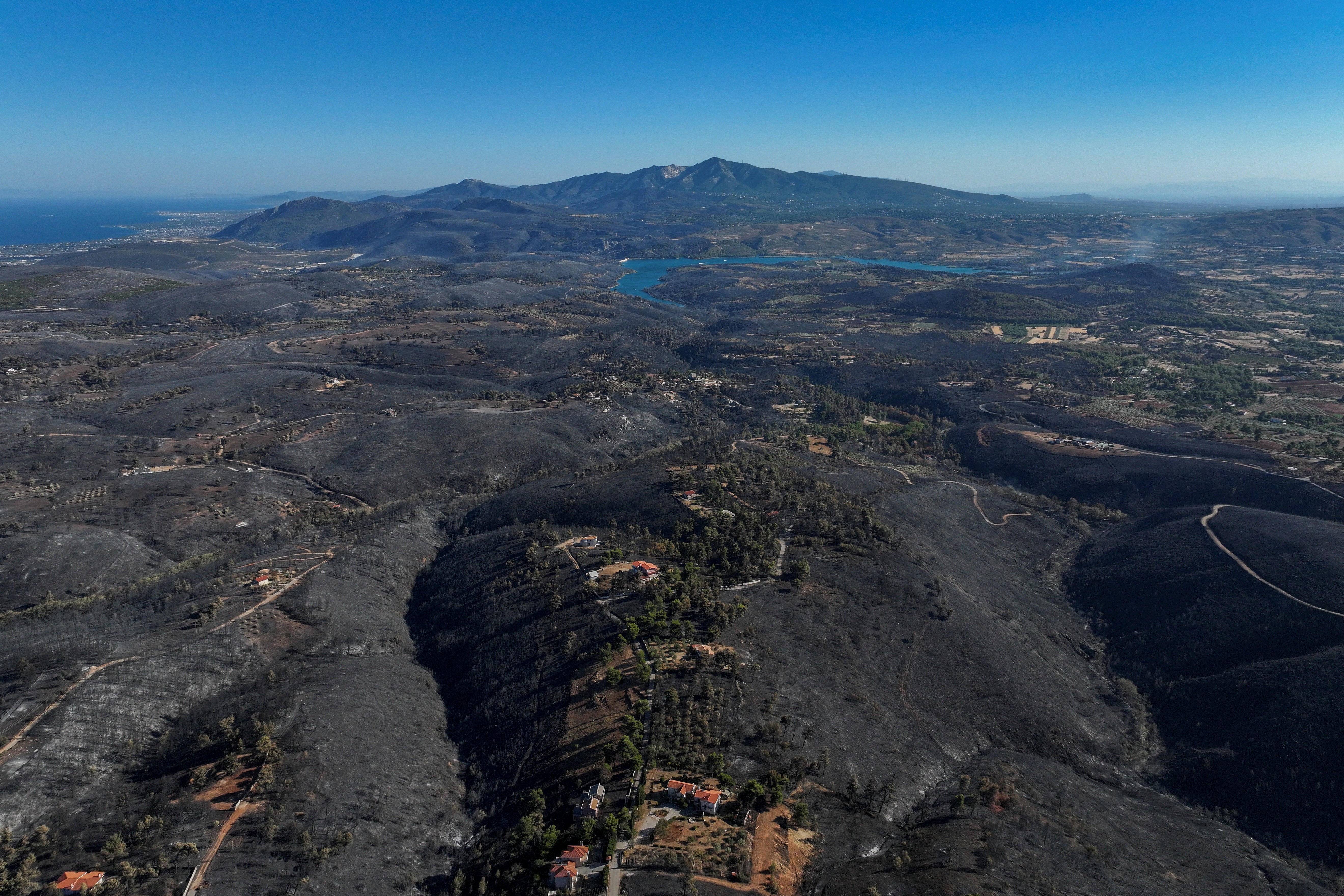 A drone view shows a charred forest area following a wildfire, in the village of Varnavas, Greece