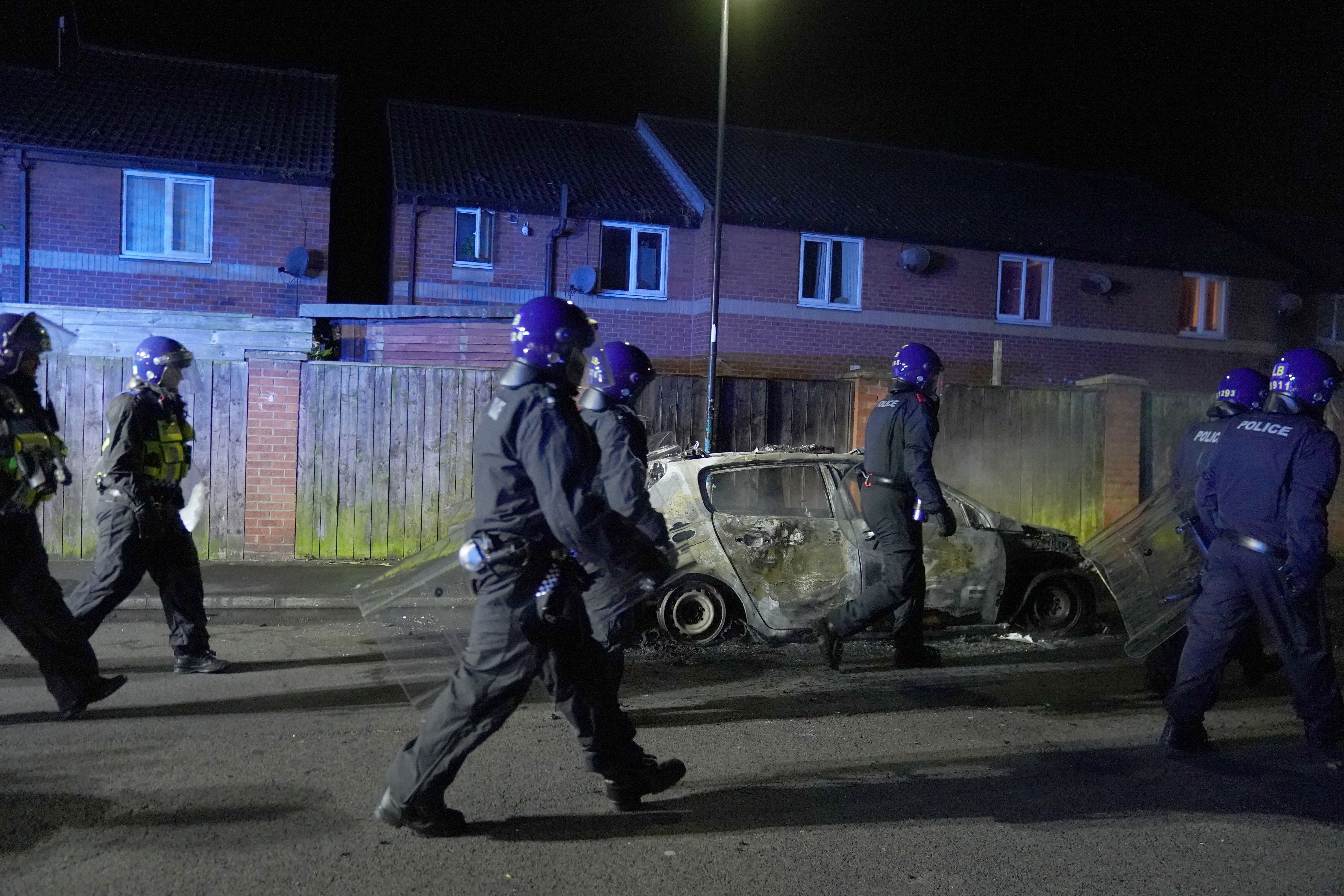 Police walk past a burnt out police vehicle on the streets of Hartlepool (Owen Humphreys/PA)