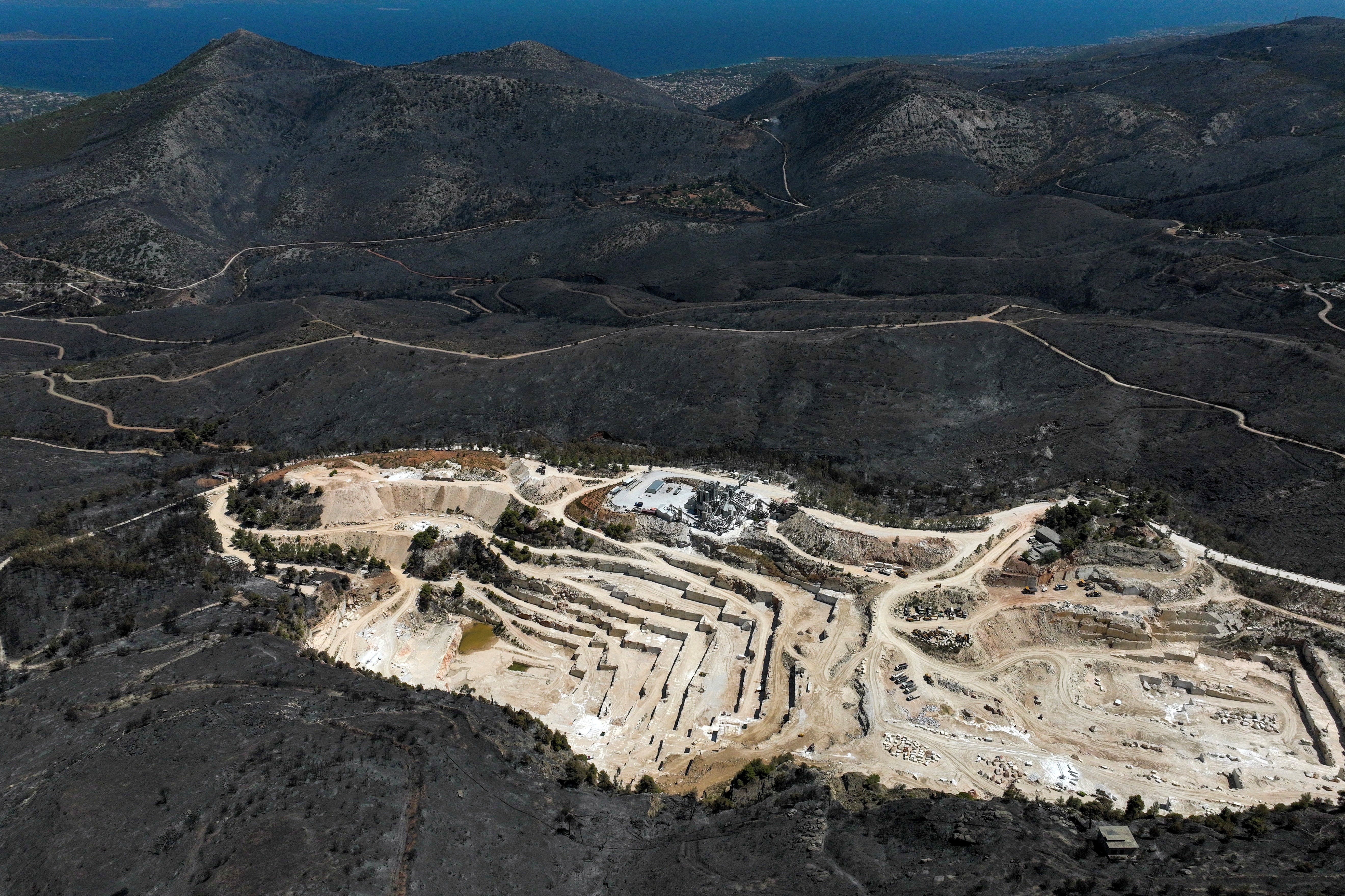 A drone view shows a charred forest area around a marble quarry following a wildfire in Dionysos, near Athens, Greece