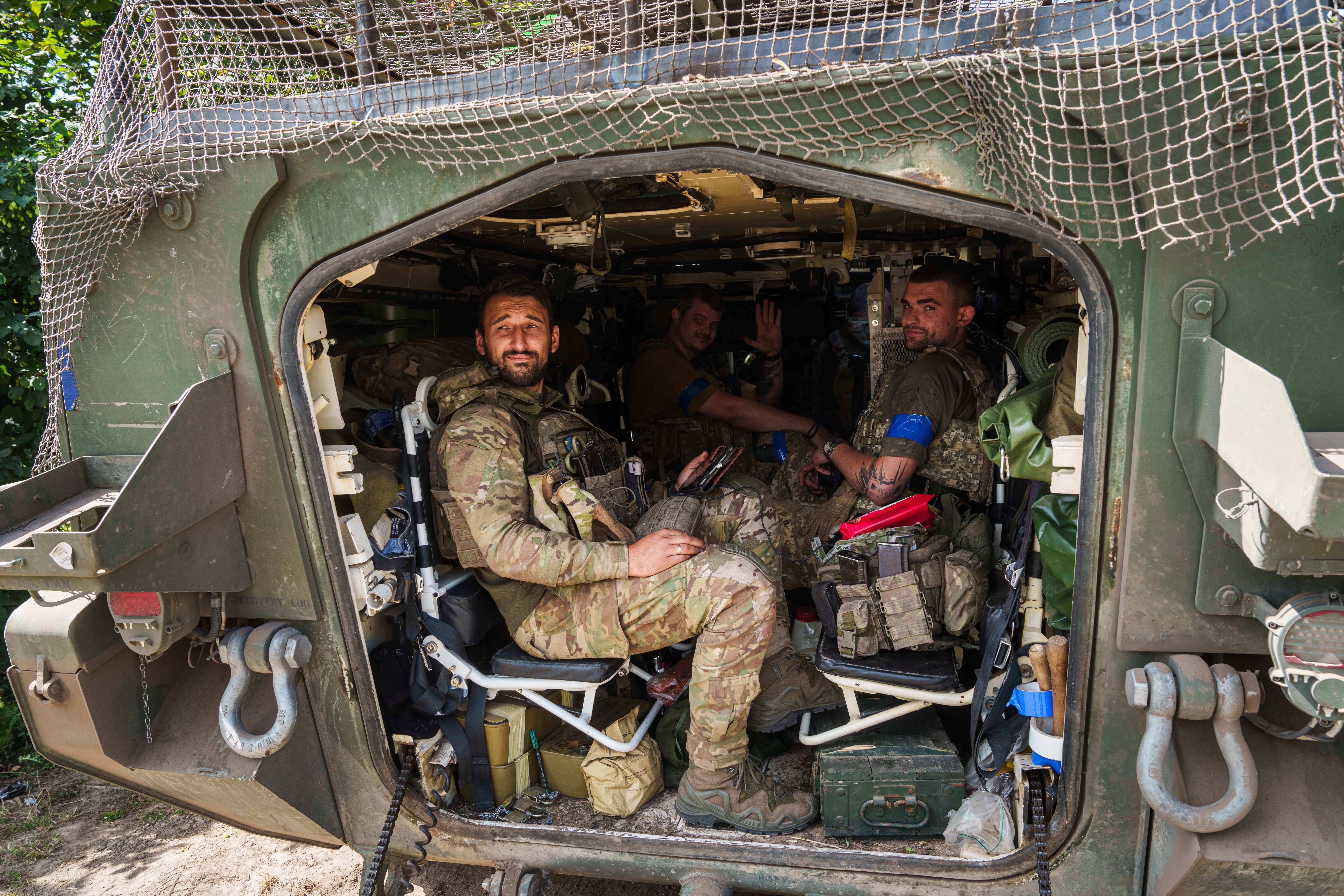 Ukrainian servicemen sit inside their armoured personnel carrier after returning from Russian Kursk region