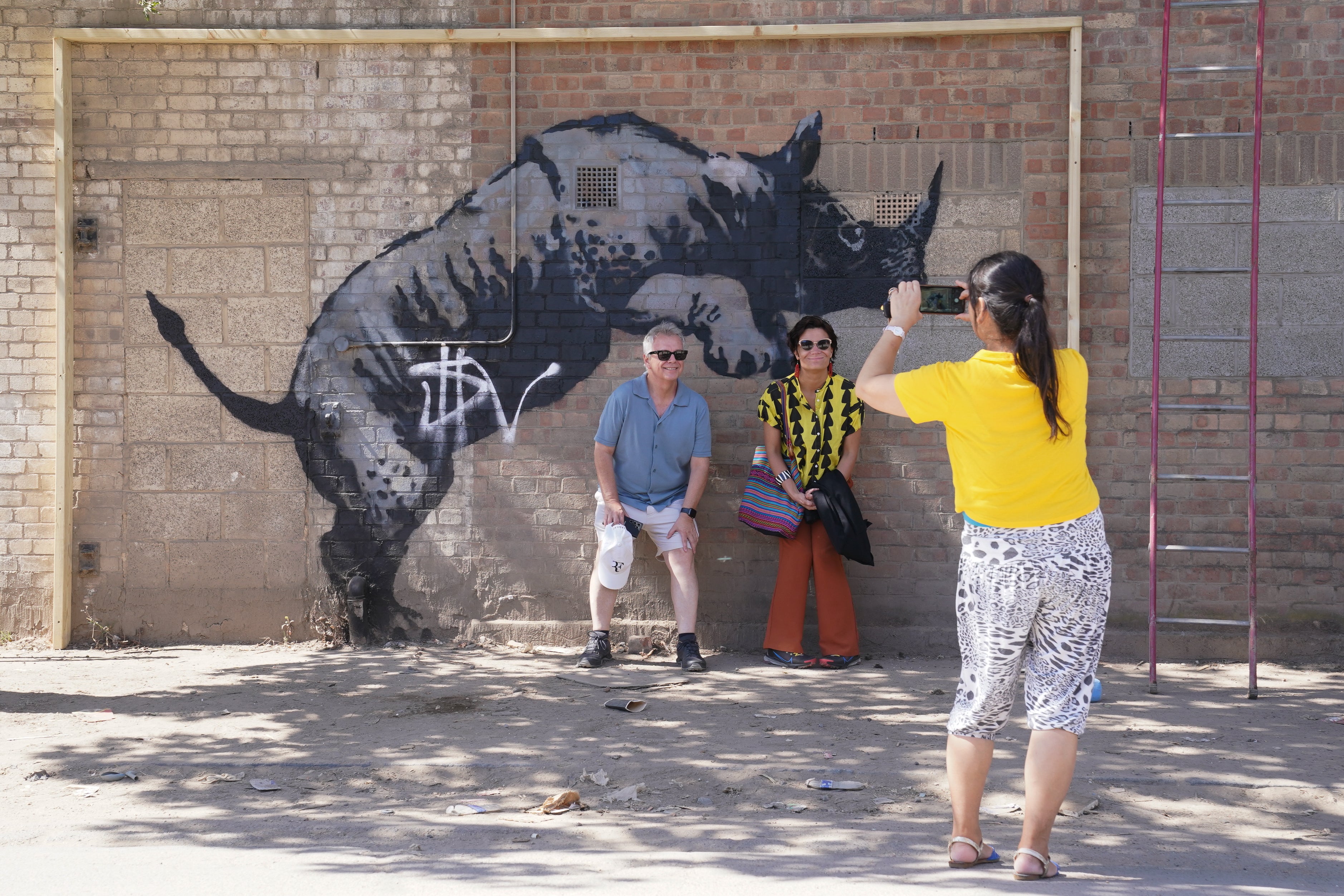 People have their picture taken by the now defaced artwork unveiled by Banksy, depicting a rhinoceros (Lucy North/PA)