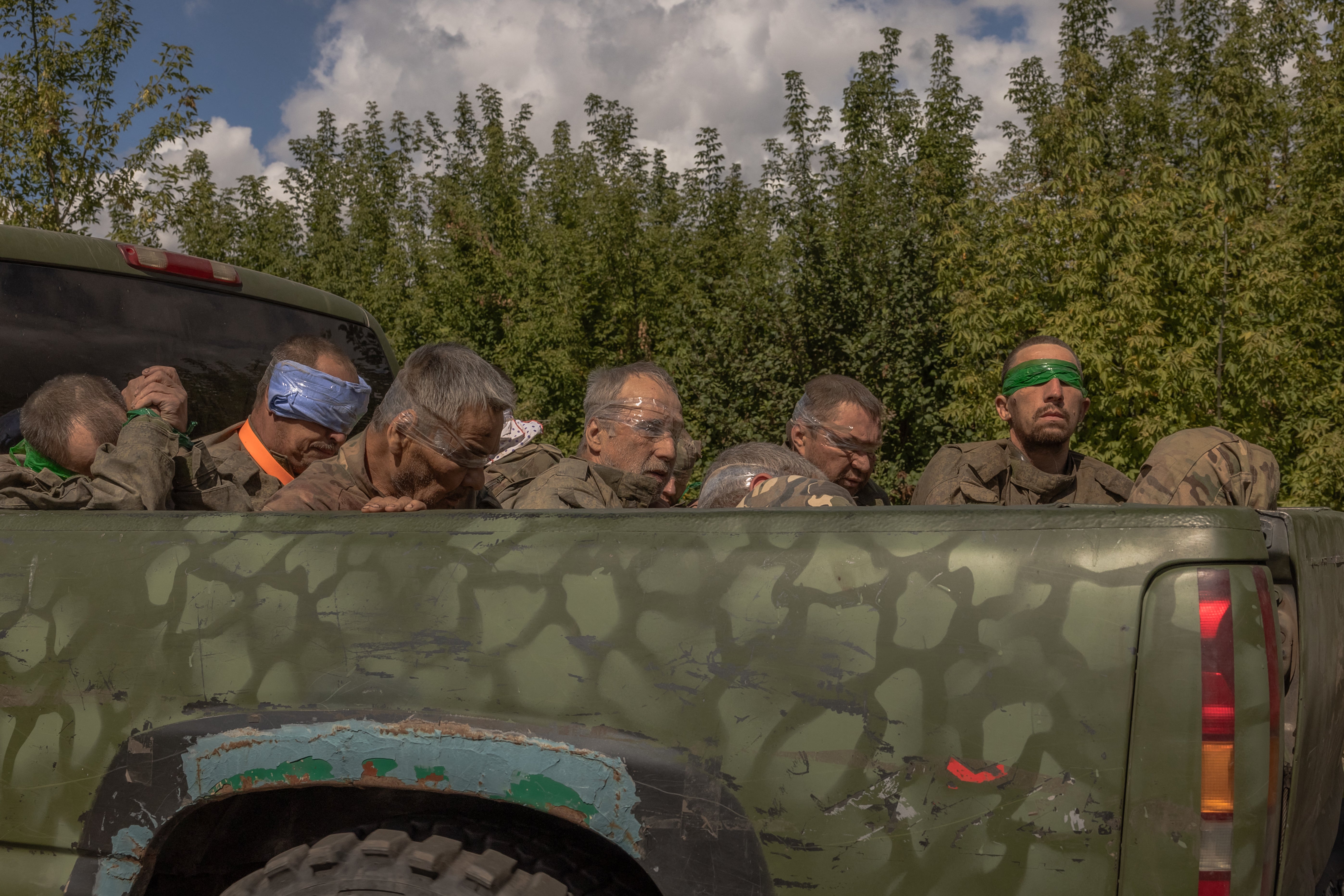 A Ukrainian military vehicle drives from the direction of the border with Russia carrying blindfolded men in Russian military uniforms