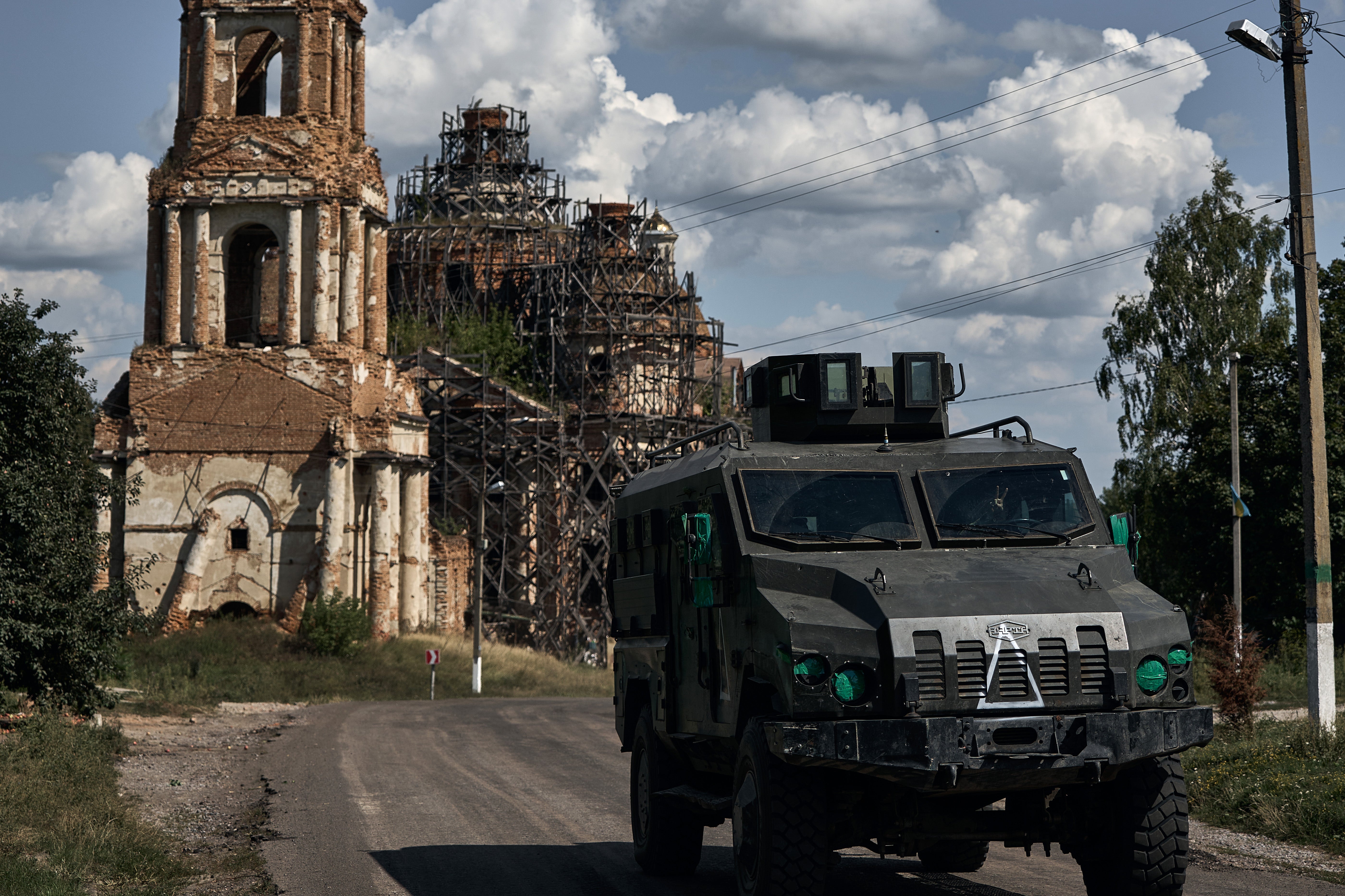 Ukrainian armored infantry vehicle ‘Roshel’ travels past an unfinished church on the road from Sumy to the border with Russia