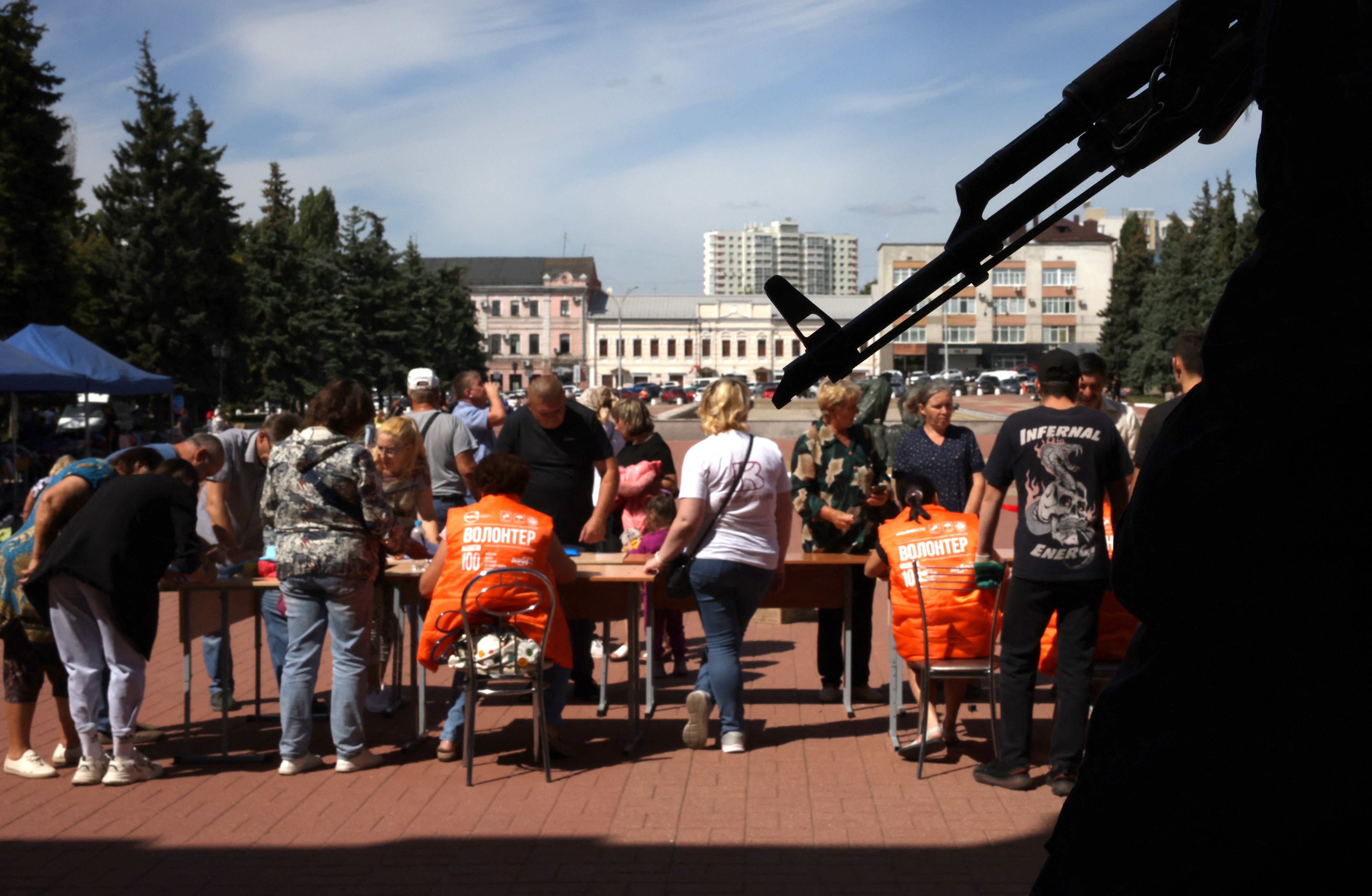 A security guard holds a weapon in front of a center for receiving war displaced persons and distributing humanitarian aid in Kursk