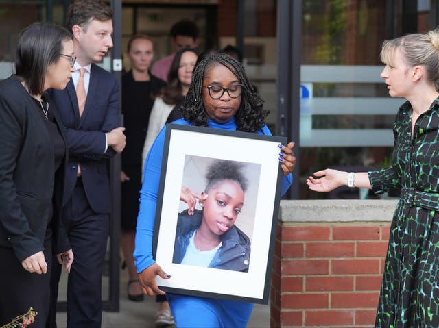 <p>Abimbola Duyile holds a picture of her daughter Hannah Jacobs outside East London Coroner’s Court </p>