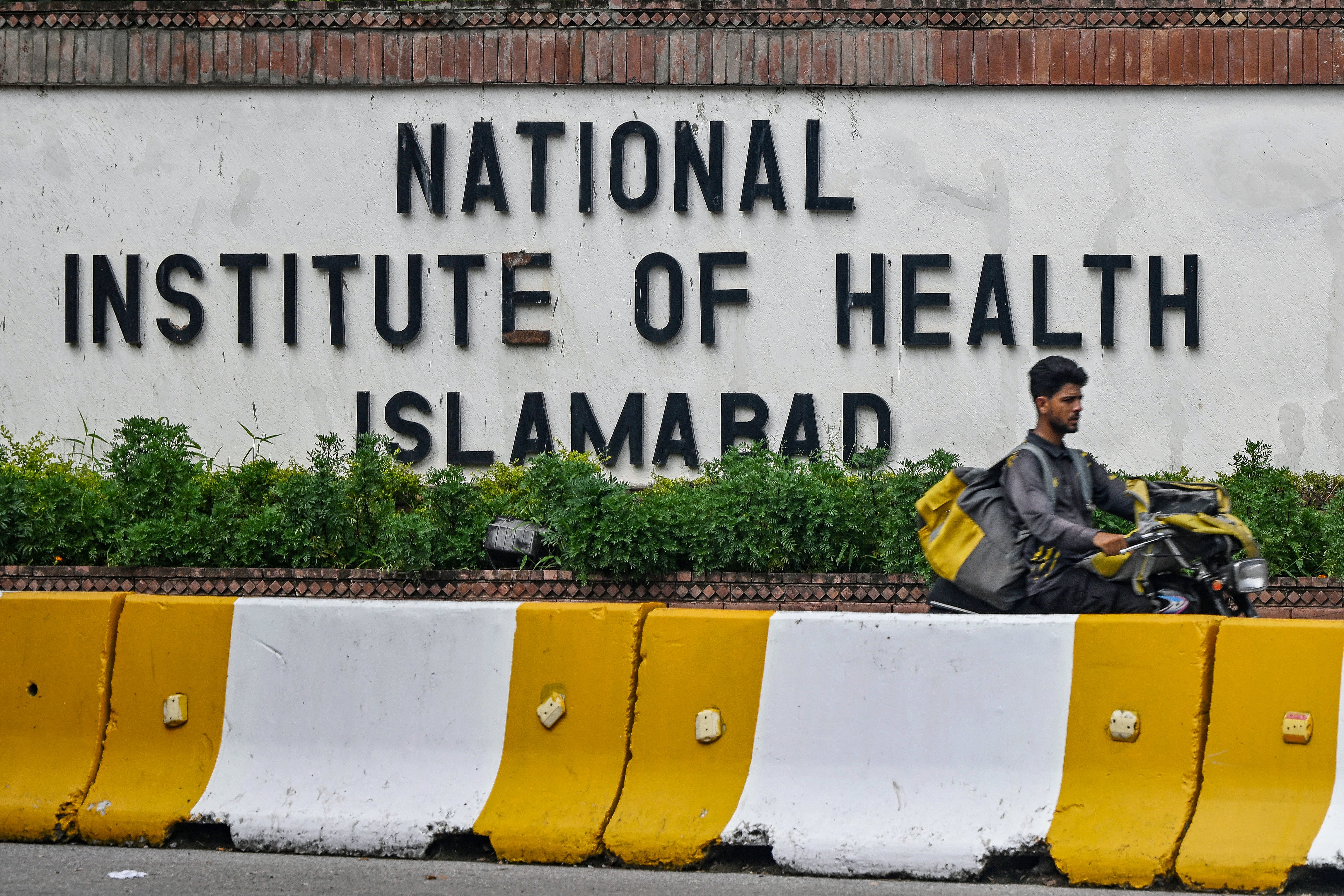 A delivery boy rides past the building of National Institute of Health (NIH), a Pakistani research institute mainly responsible for biomedical and health related research, in Islamabad on August 16, 2024. Pakistan said on August 16 it had confirmed a case of mpox