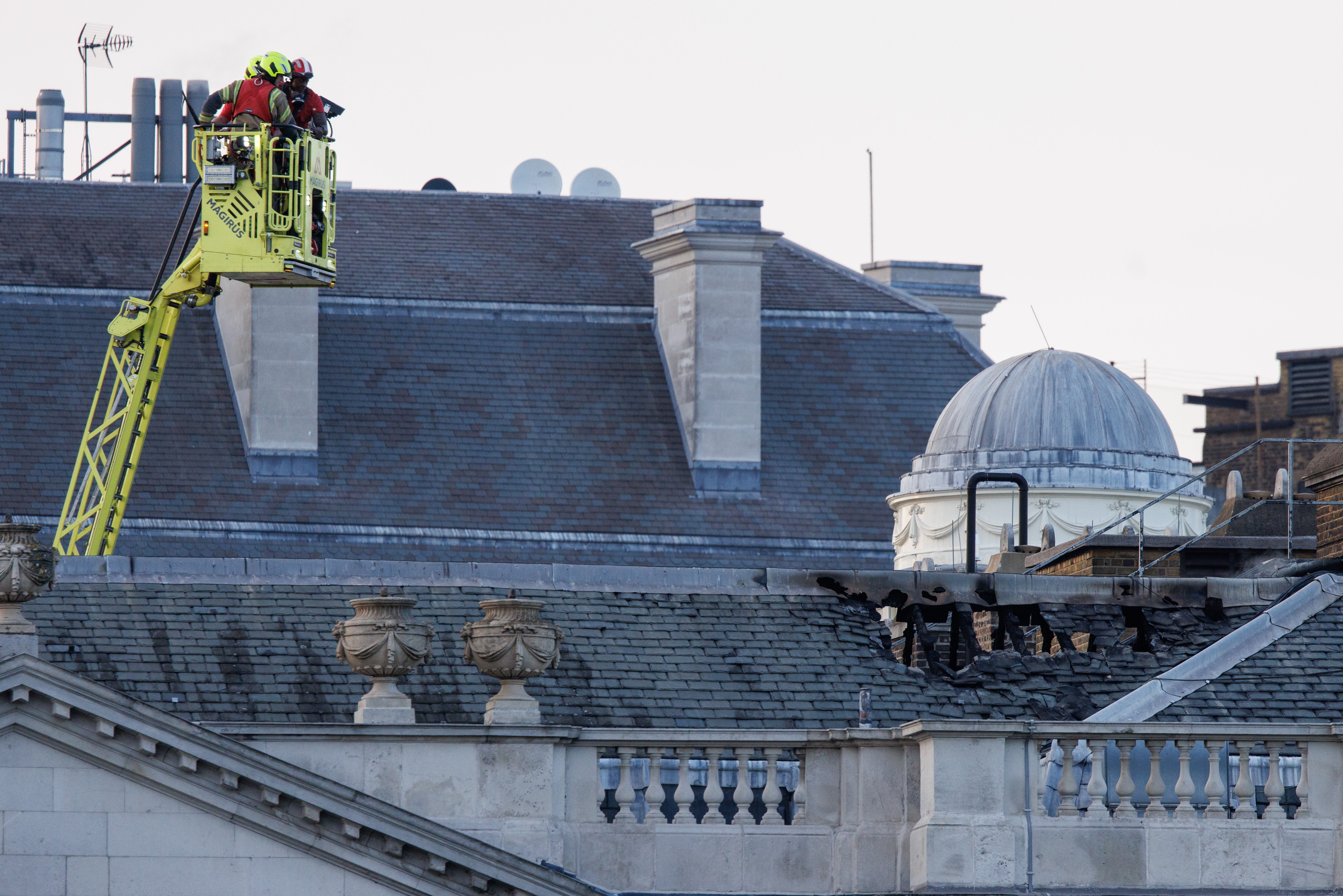 Firefighters look down at the damaged roof.