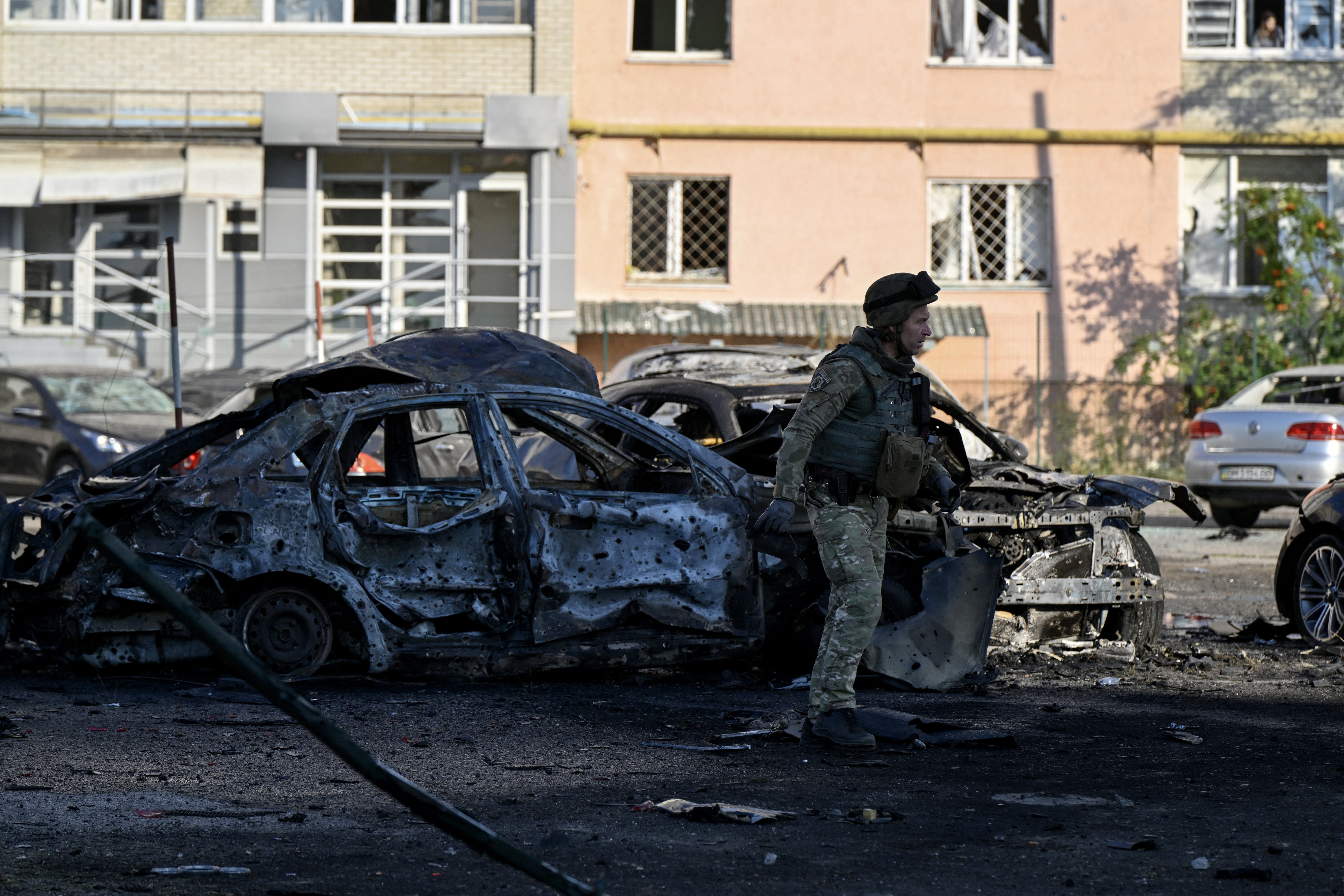 A police expert walks past burned cars at the site of a Russian strike in the city of Sumy on August 17, 2024