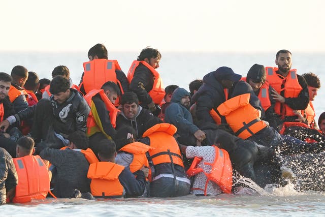 A group of people thought to be migrants wade through the sea (PA)