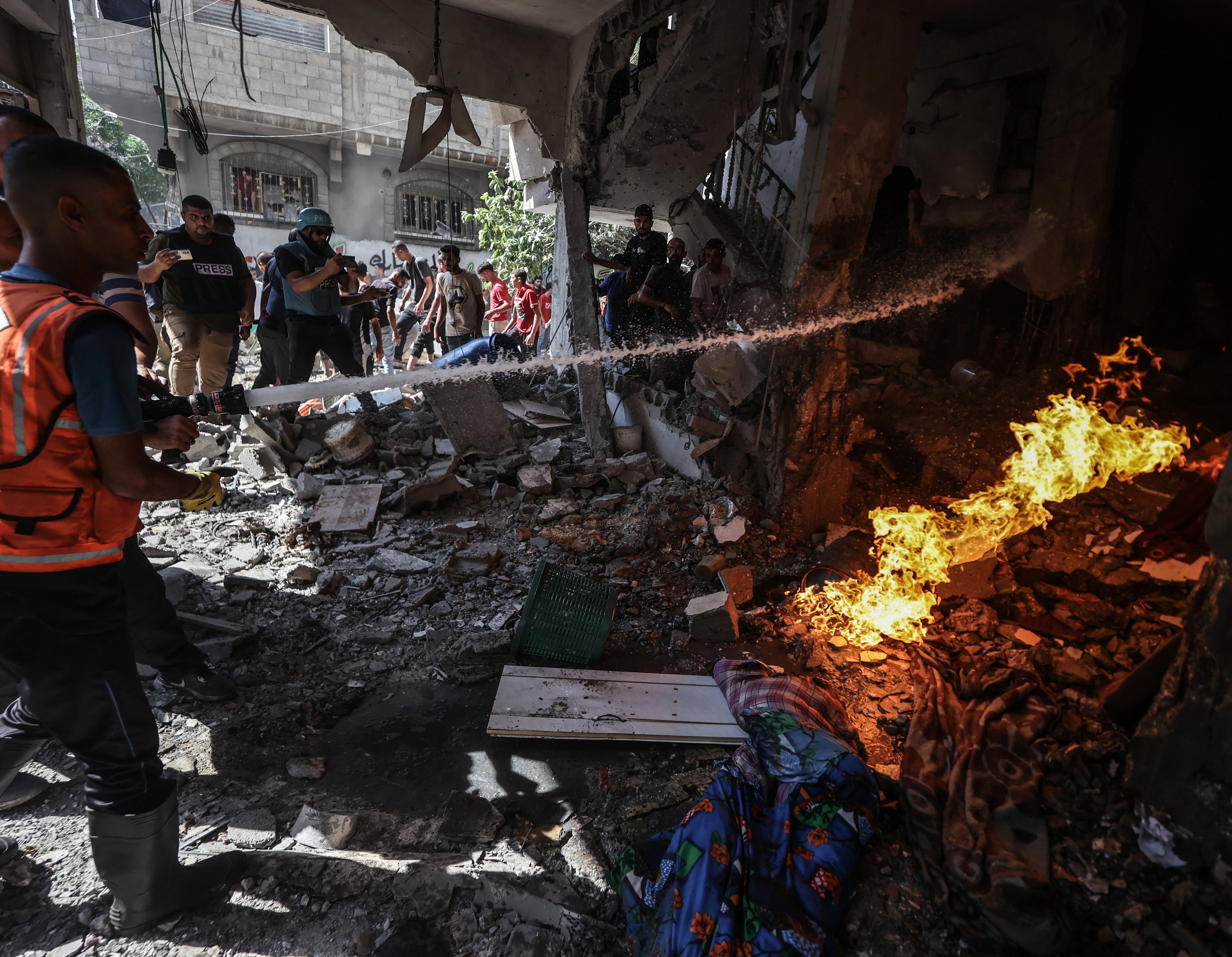 Firefighters and civilians try to extinguish a fire sparked by an Israeli army attack in Gaza