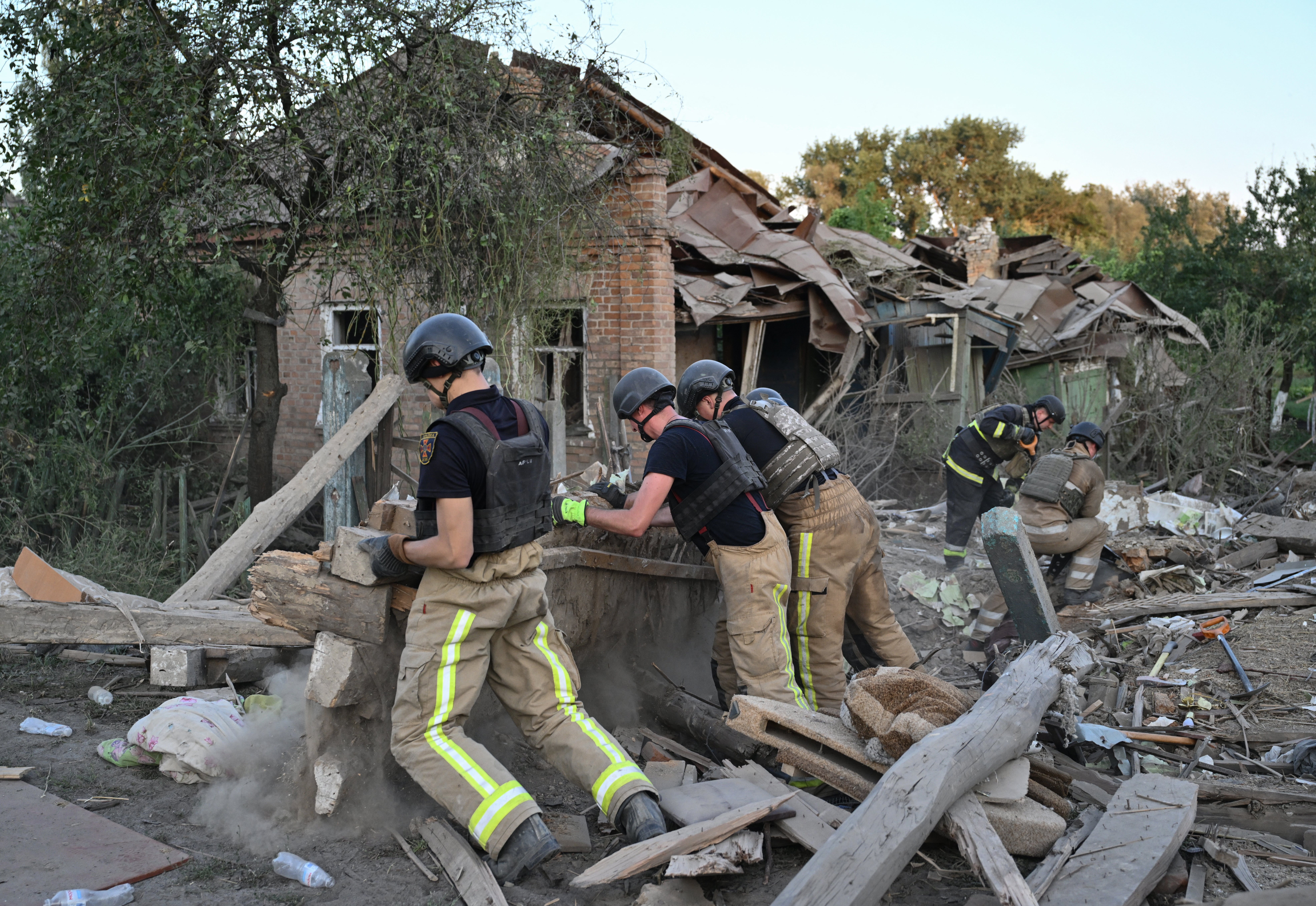 Rescuers clear debris of a house destroyed following a strike in the town of Bilopillya, near the Russian border in the Sumy region