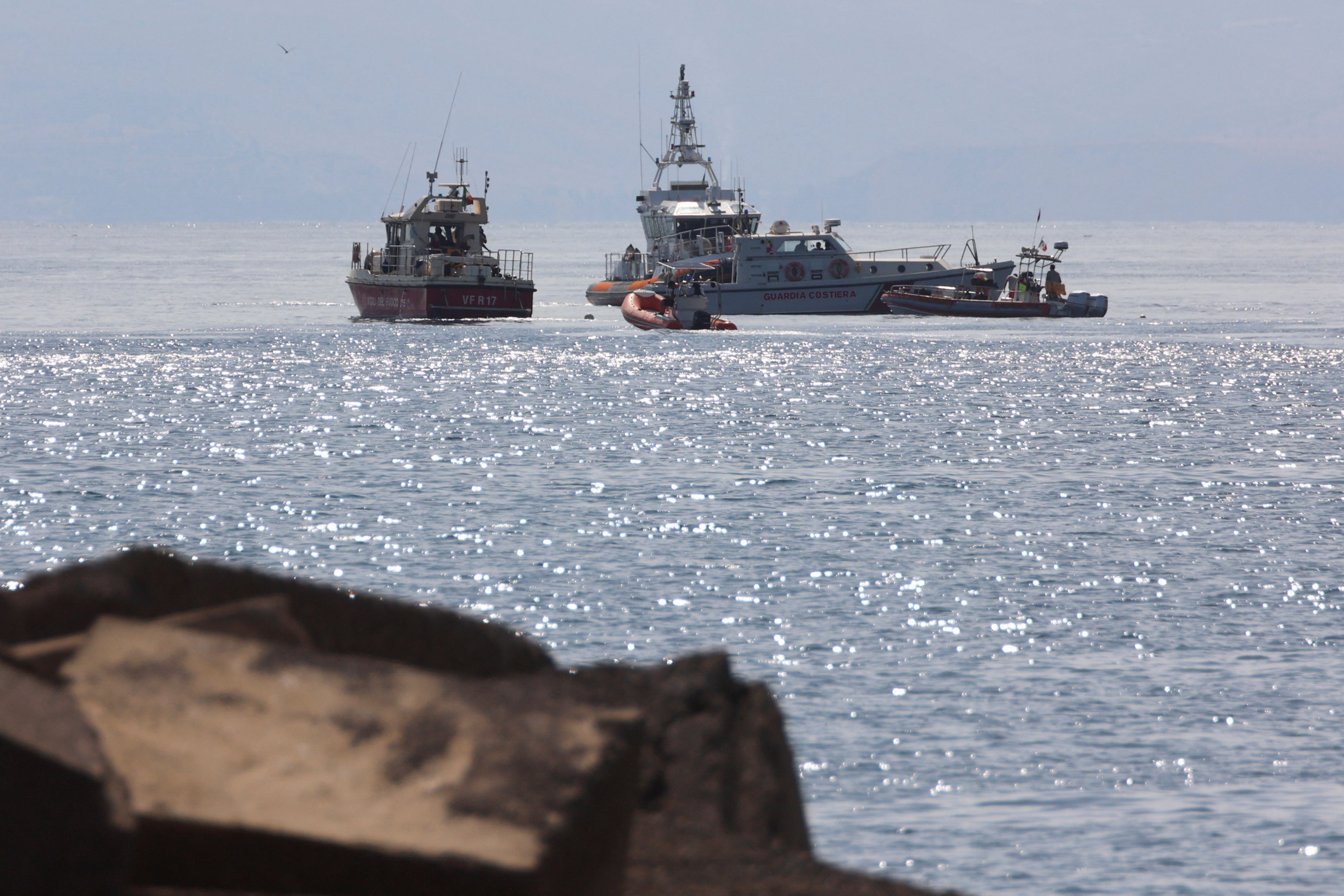 Emergency services work near the scene where a sailboat sank in the early hours of Monday off the coast of Porticello