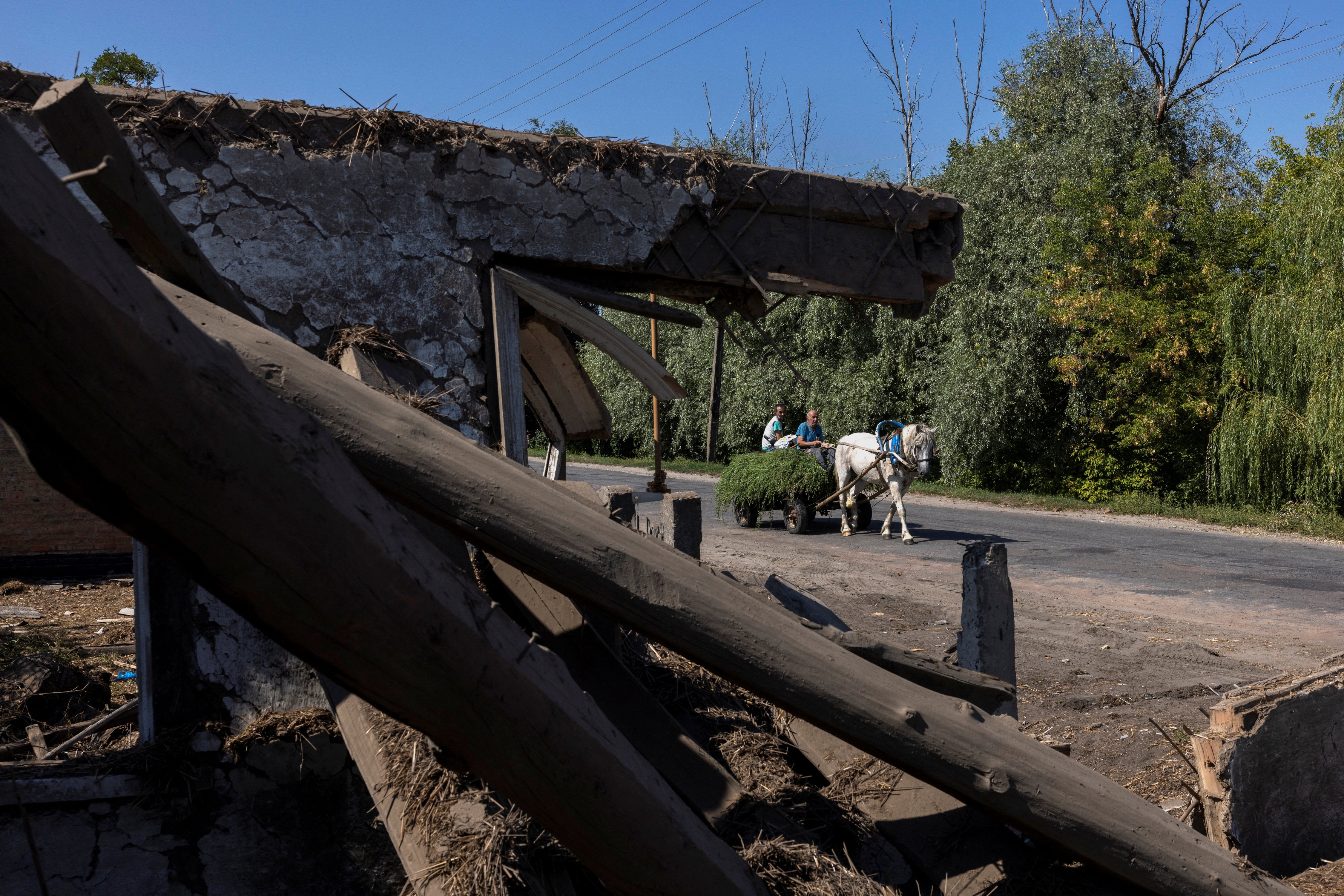 A horse-drawn cart goes past a residential house that was destroyed in a recent Russian airstrike in Bilopillia near the Russian border,