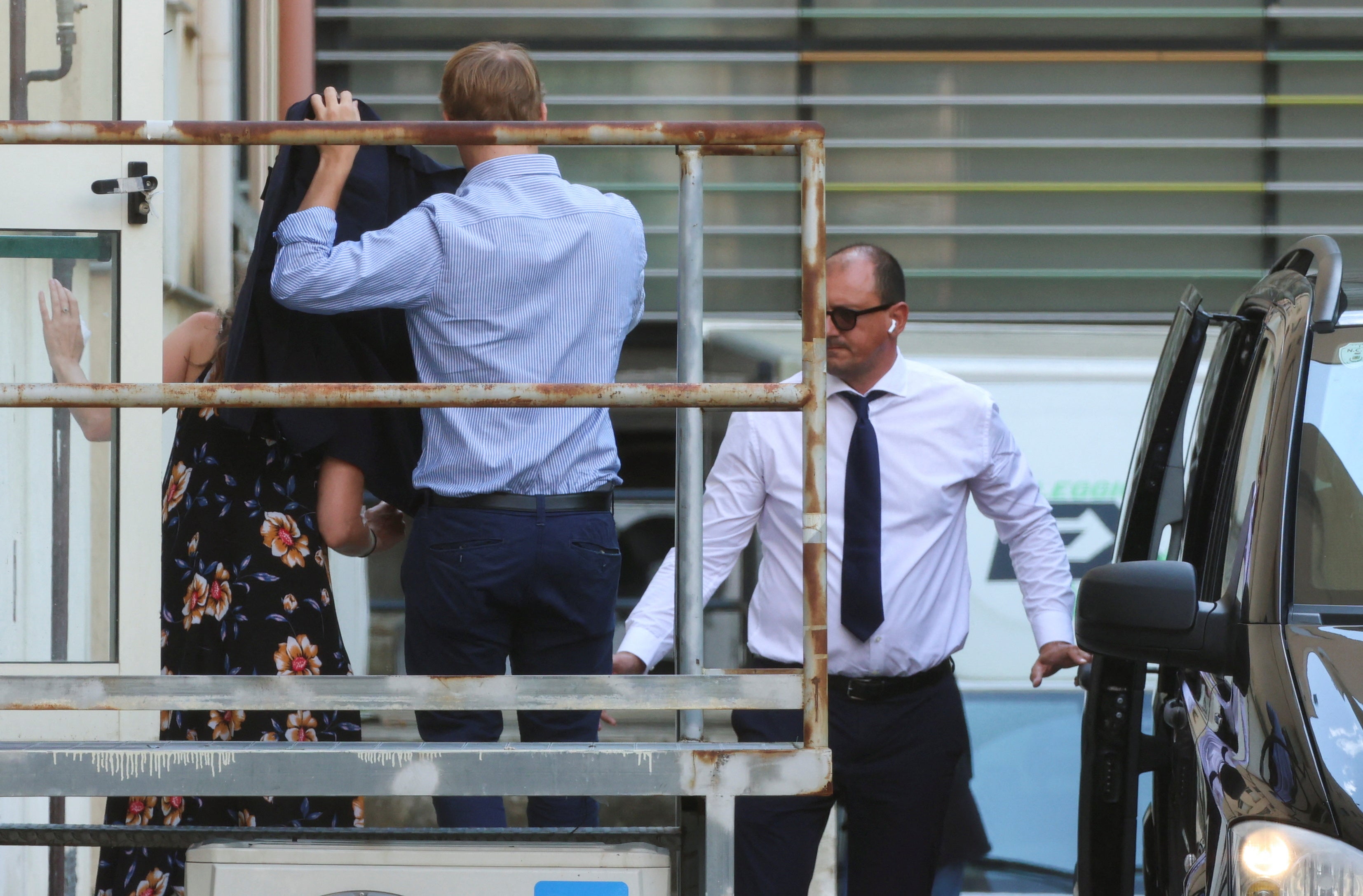 Charlotte Golunsky’s face covered by an officer from the British embassy as she leaves hospital in Italy