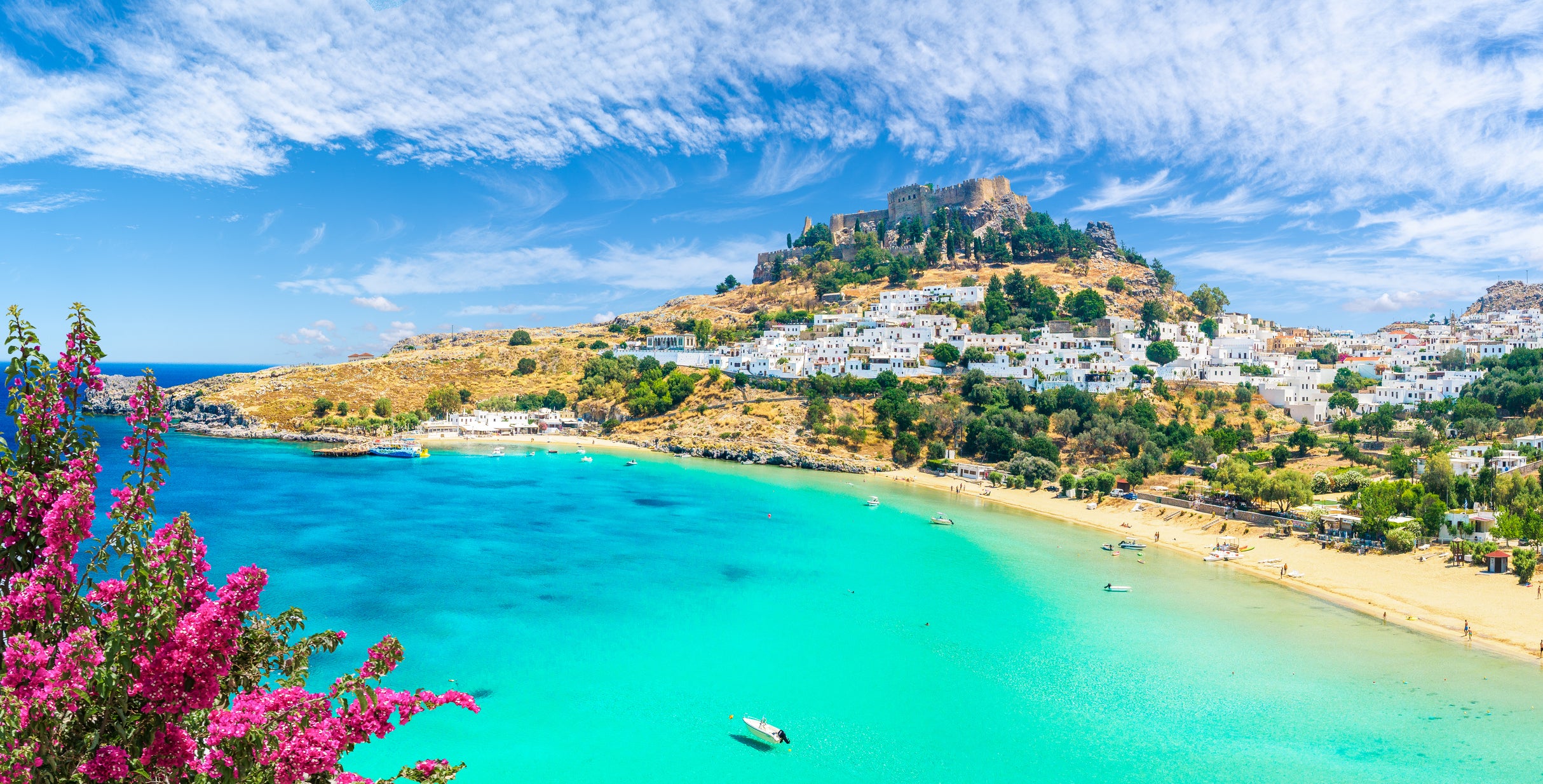 Blue waters, a beach and castle at Lindos village on Rhodes, Greece