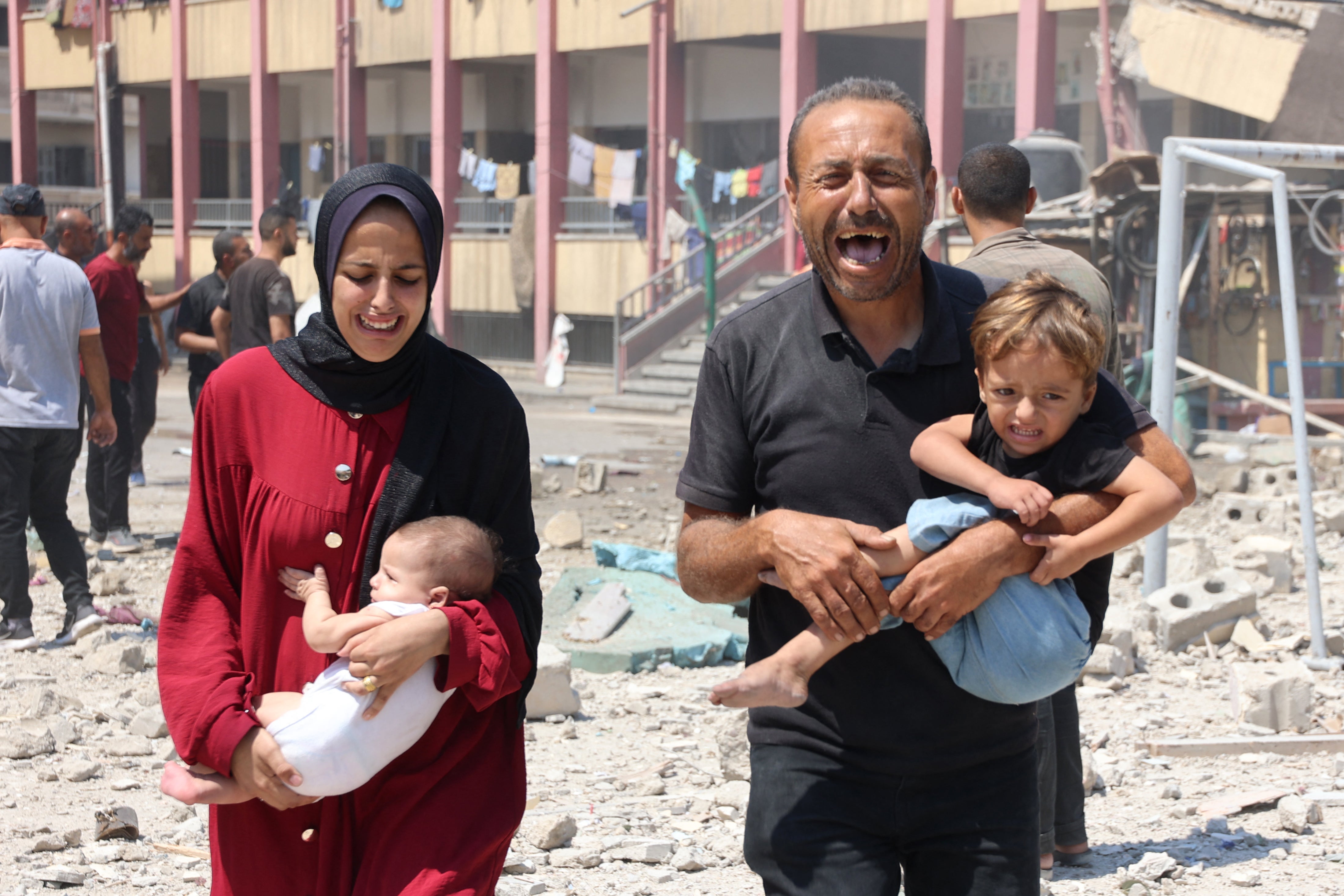 Palestinians carry their children as they flee after the Israeli attack on a school in Rimal, Gaza City