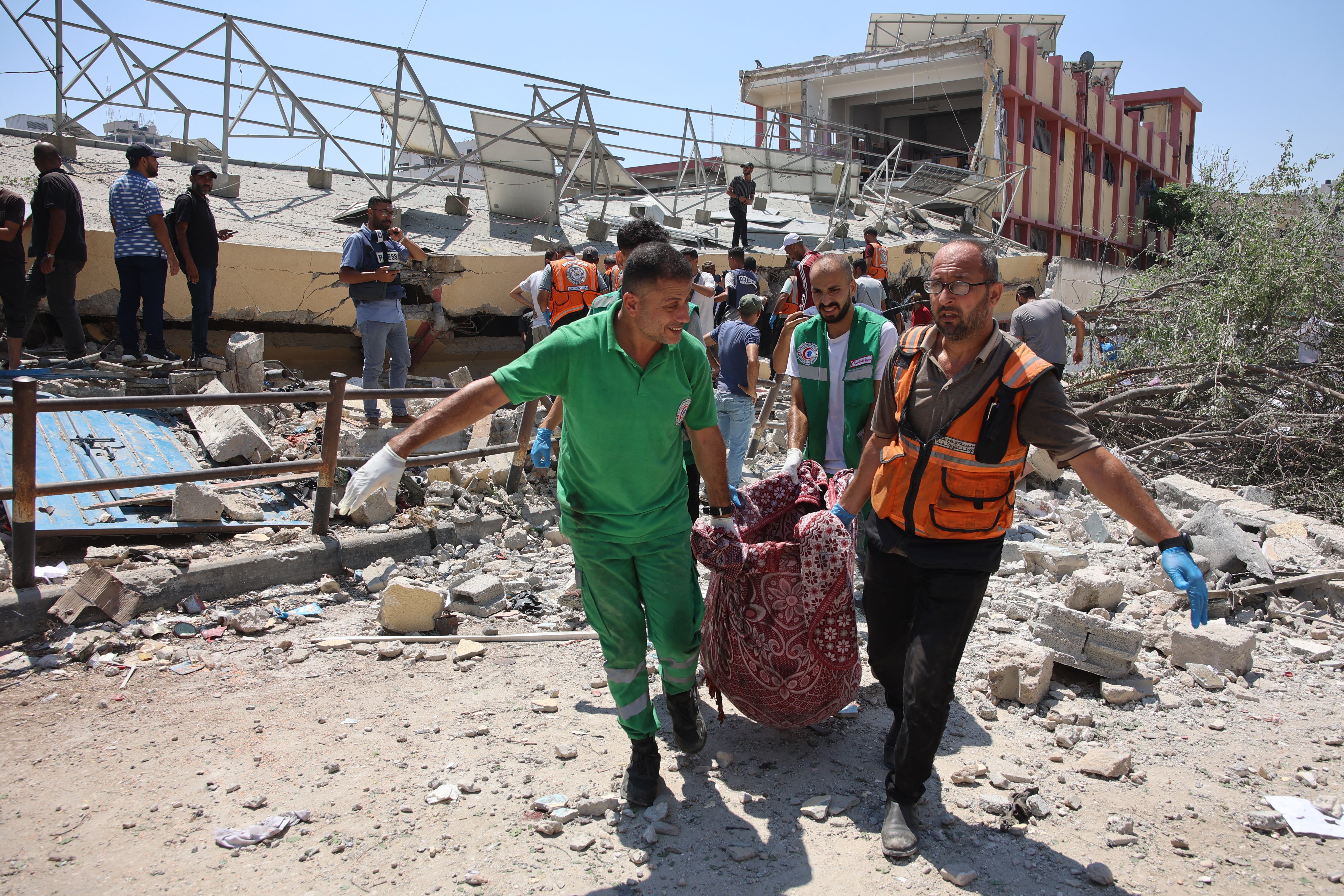 A body is carried from the site of the Israeli strike on a school in Rimal, Gaza City on Tuesday