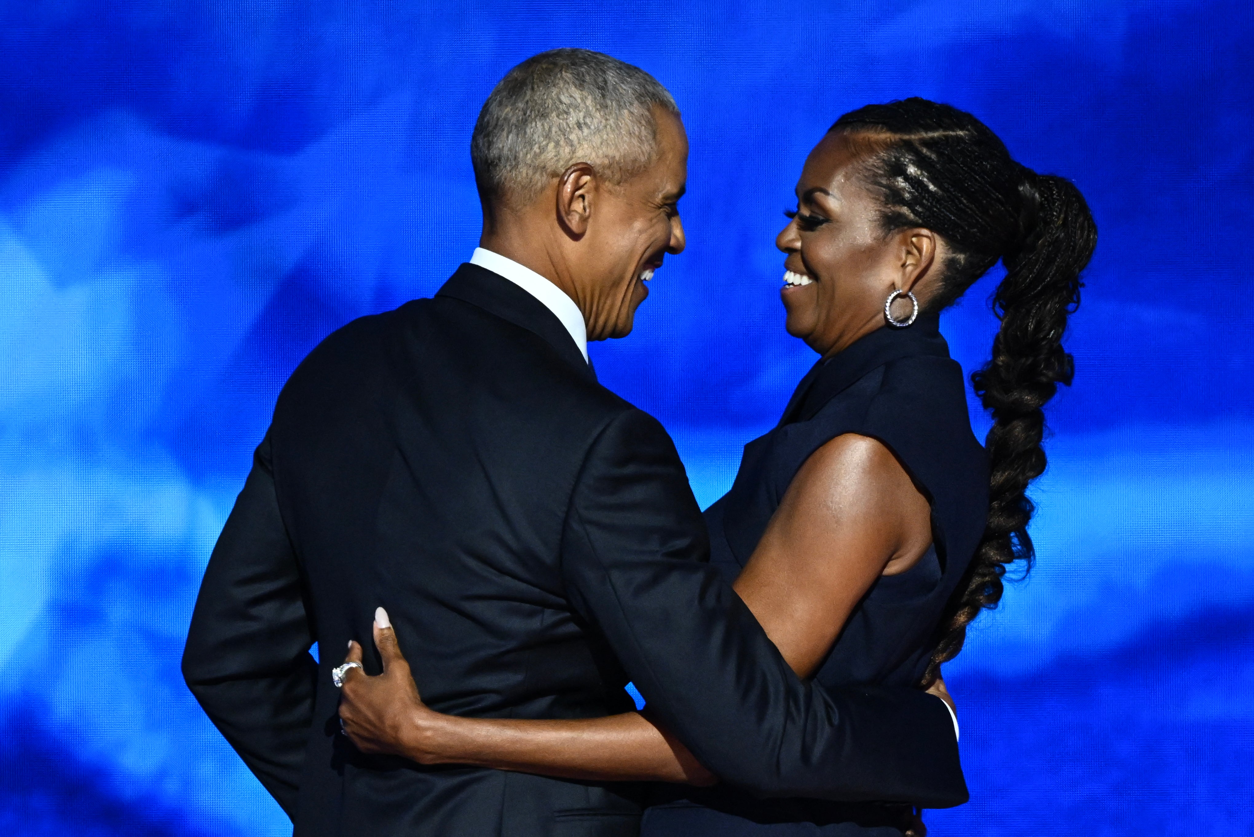 El ex presidente estadounidense Barack Obama abraza a su esposa y ex primera dama Michelle Obama después de presentarla en el segundo día de la Convención Nacional Demócrata (DNC) en el United Center en Chicago, Illinois, el 20 de agosto de 2024. La vicepresidenta Kamala Harris aceptará formalmente la nominación para presidenta del partido en el Comité Nacional Demócrata, que se celebrará del 19 al 22 de agosto en Chicago. (Foto de MANDEL NGAN/AFP) (Foto de MANDEL NGAN/AFP vía Getty Images)